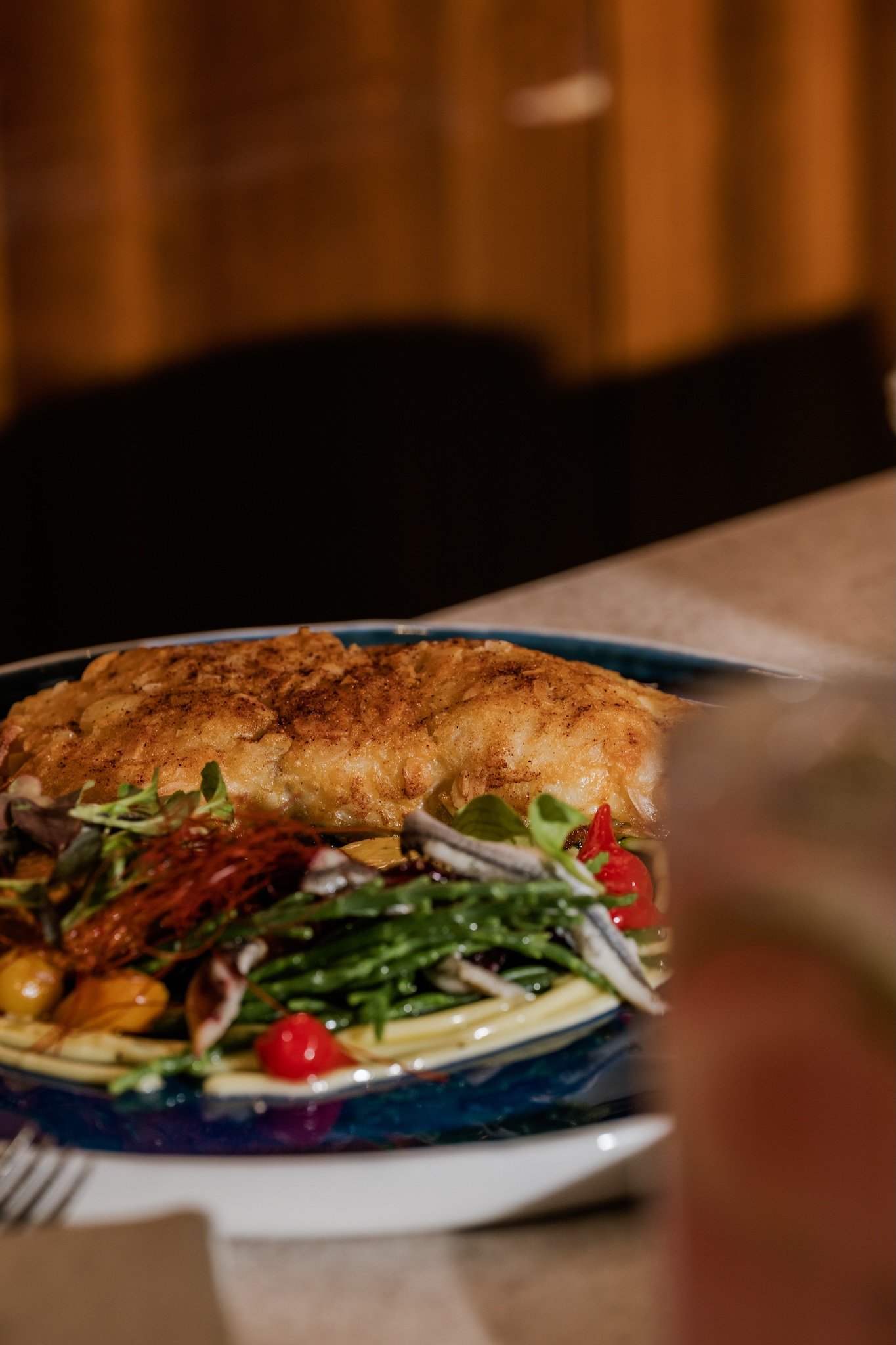 Breaded cutlet with salad on a patterned plate, restaurant food photography