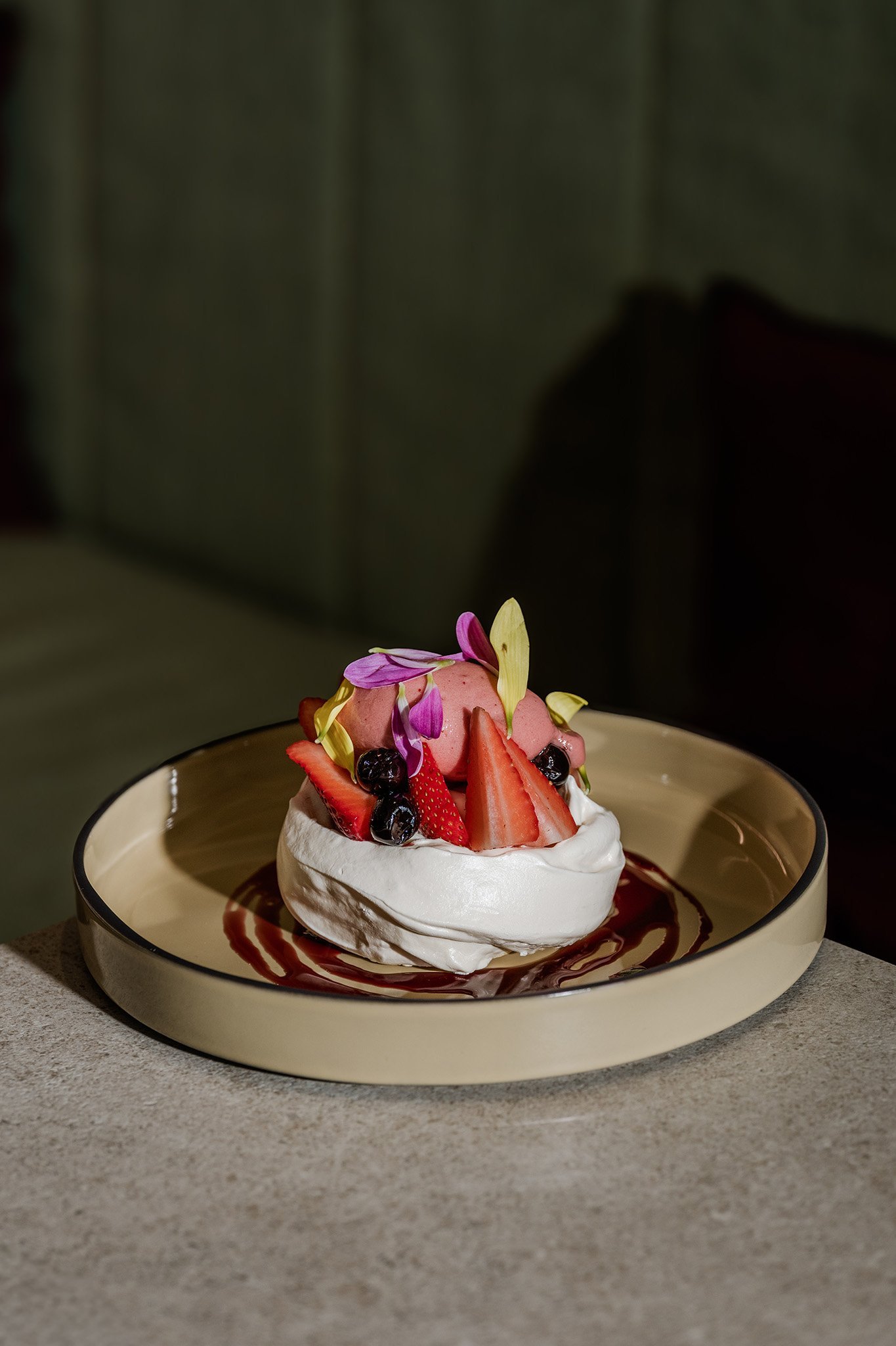 Dessert topped with strawberries and edible flowers on a ceramic plate, food photography