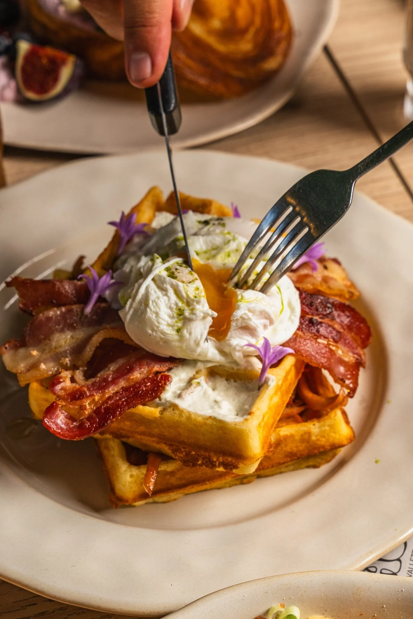 Eggs Benedict with bacon being cut with a fork, brunch food photography