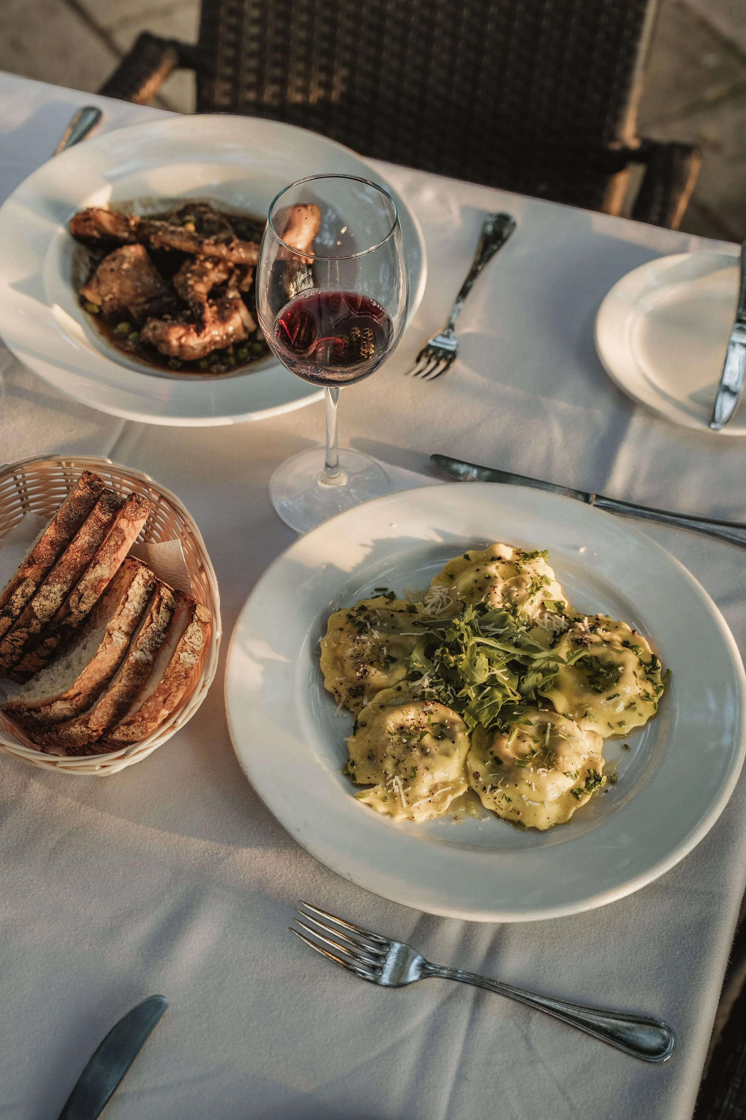 Restaurant table with pasta and grilled meat on white linen, food photography Malta