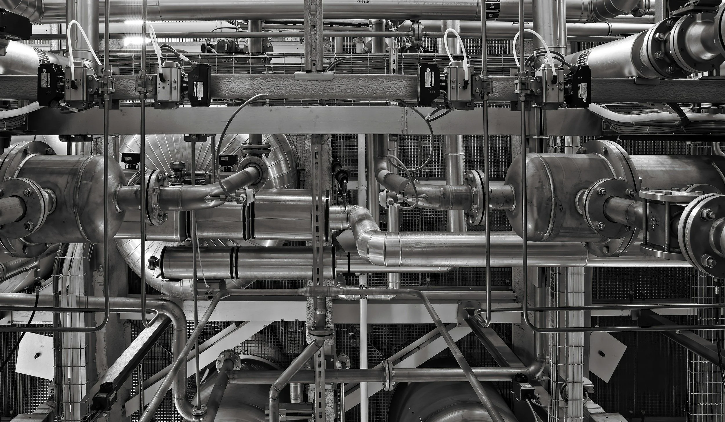 Industrial facility filled with stainless steel pipes, valves, pumps, and process equipment