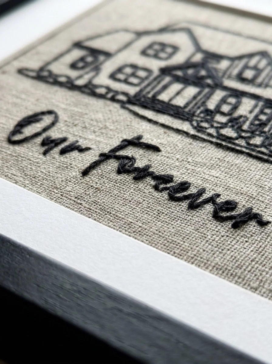 Close-up of a fabric patch with embroidered black outline of a house and the word 'Our Home' underneath.