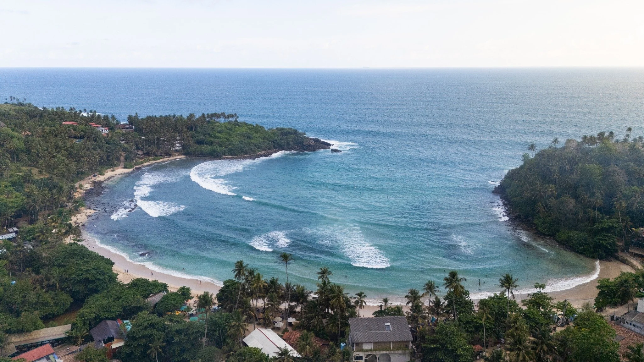 Aerial view of a palm-fringed bay and surf on Sri Lanka’s southern coast.