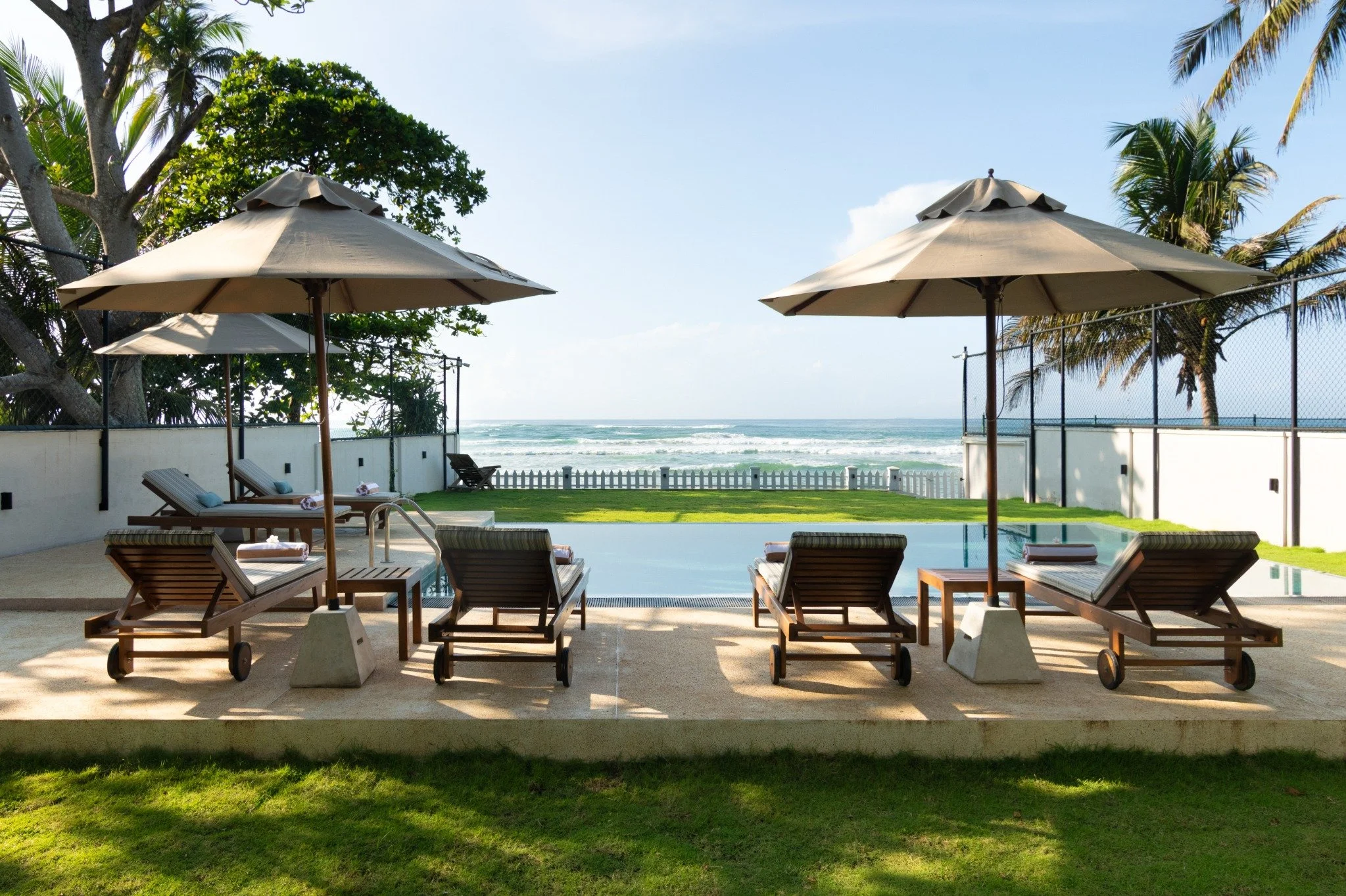 Sun loungers and parasols beside SAYU’s private pool overlooking the Indian Ocean.