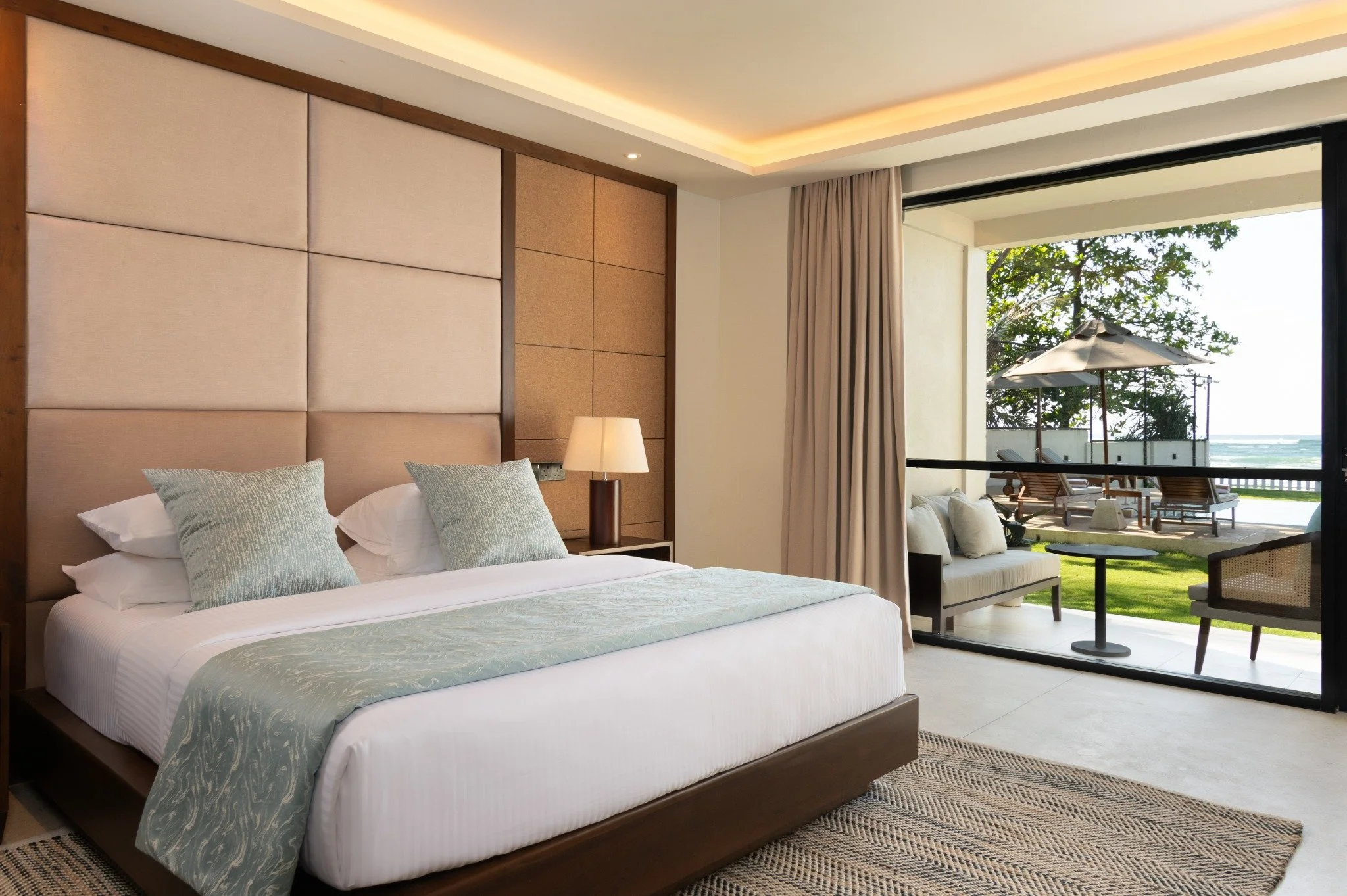 King bedroom at SAYU with seating and a private terrace facing the pool and ocean.