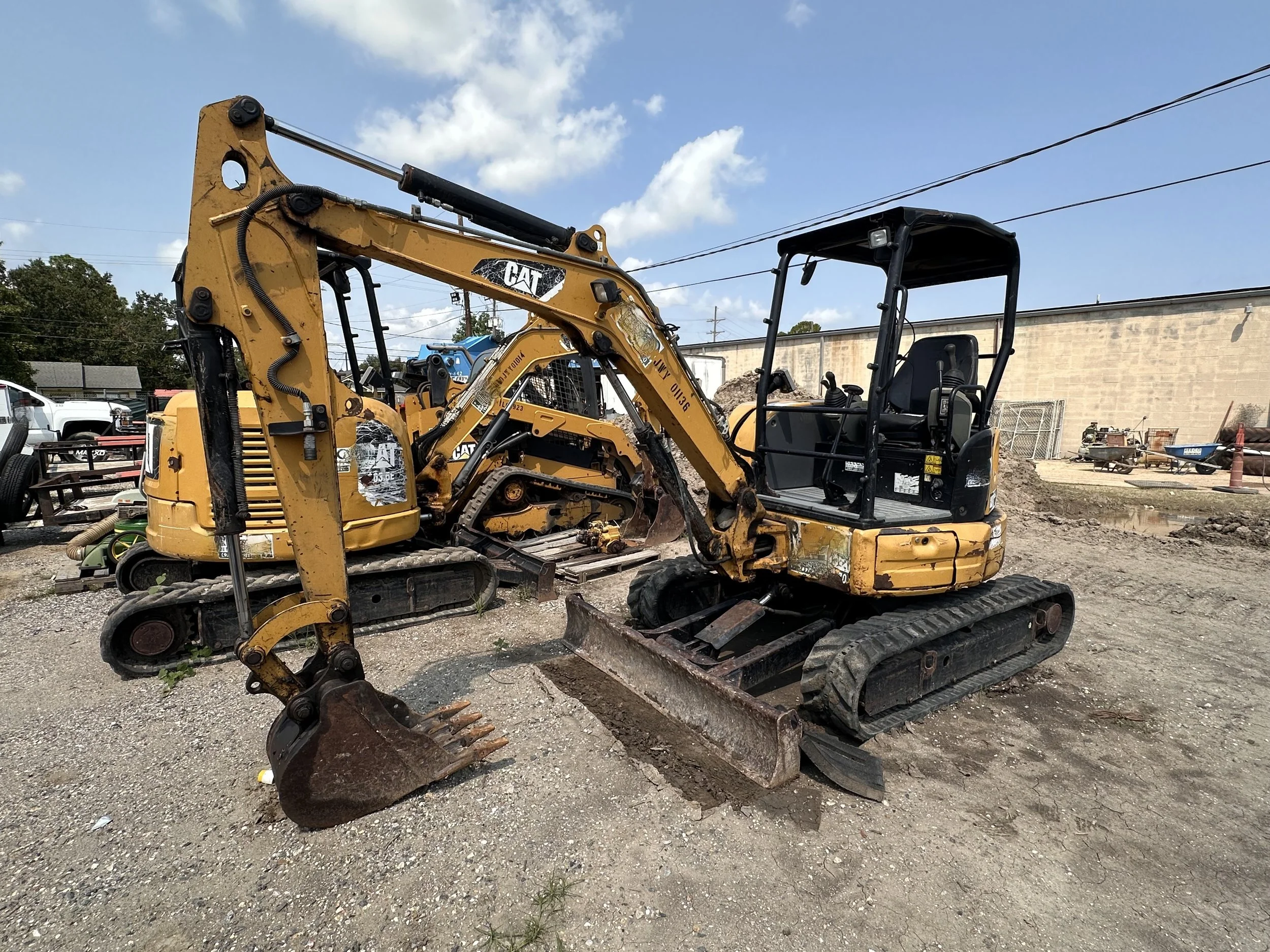 Yellow Caterpillar excavators parked at a construction equipment yard under a blue sky