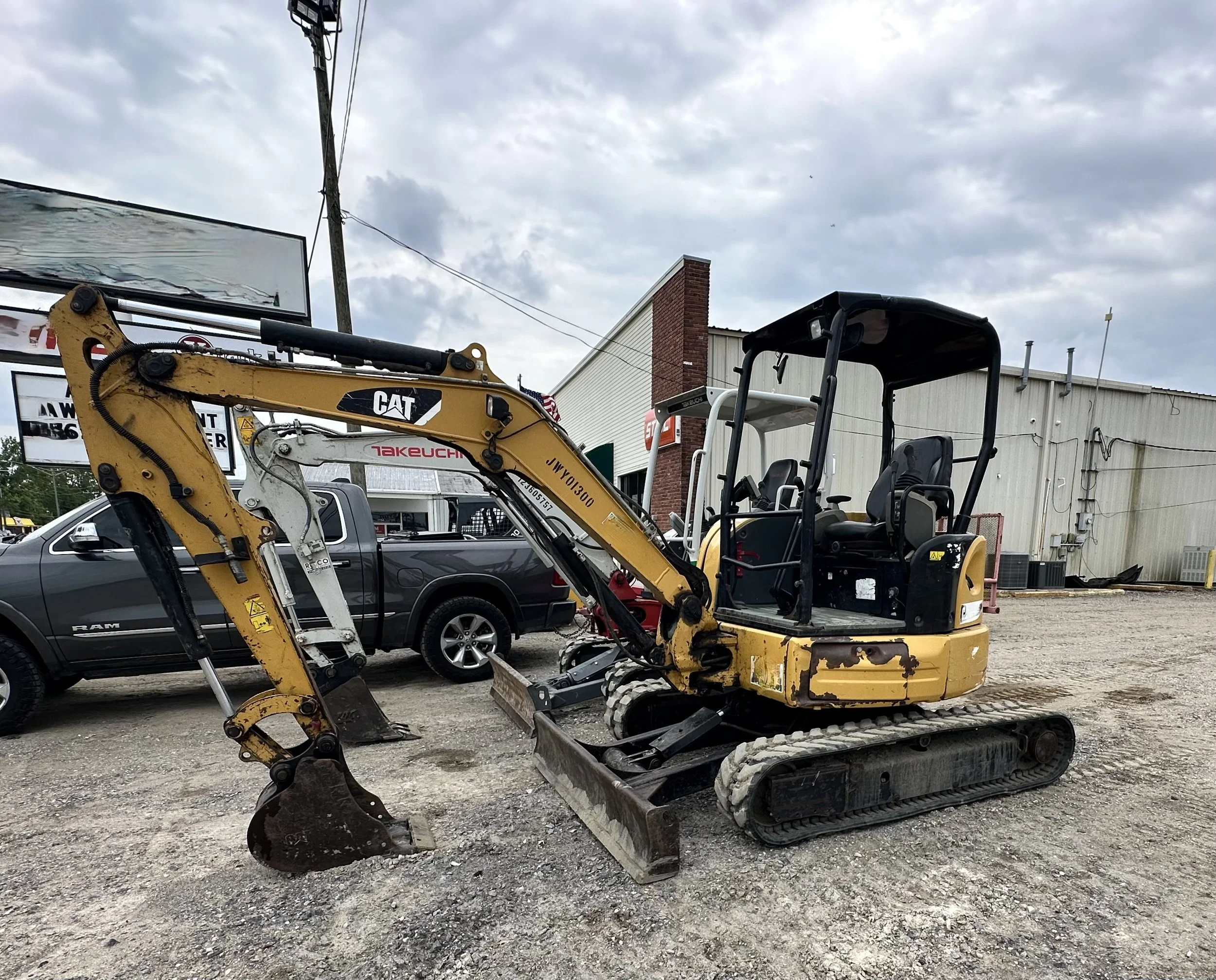 Yellow CAT and Takeuchi tracked mini excavators parked outside a construction equipment dealership.