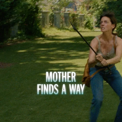 A woman in a tense stance holding a spear in a grassy park with trees and a fence in the background, with the words 'Mother Finds a Way' overlayed.
