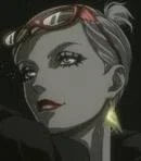 Close-up of a woman with short hair, wearing makeup, in a dark setting.