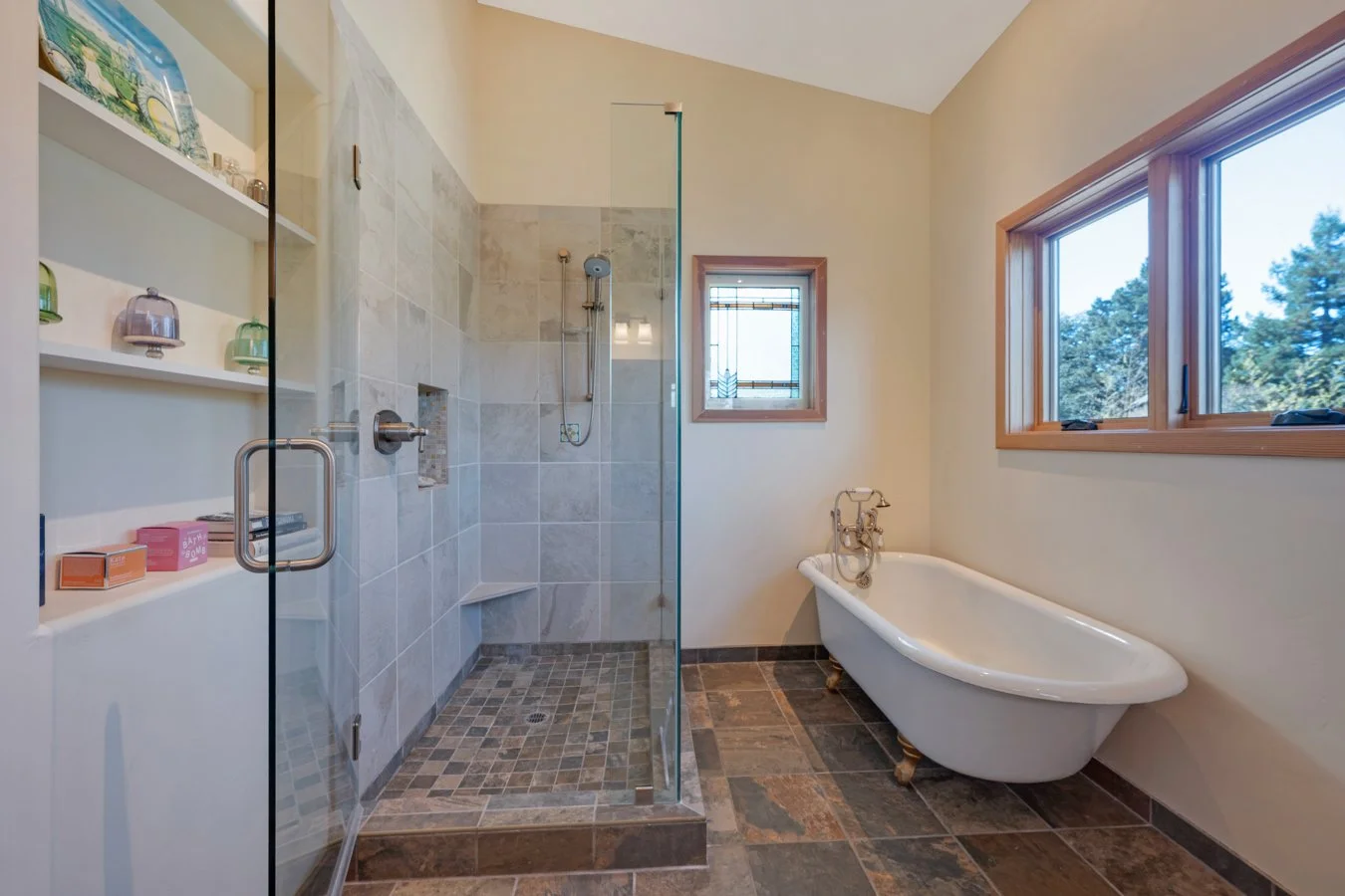 Bathroom with glass-enclosed shower, a freestanding bathtub, two windows, and a tiled floor.