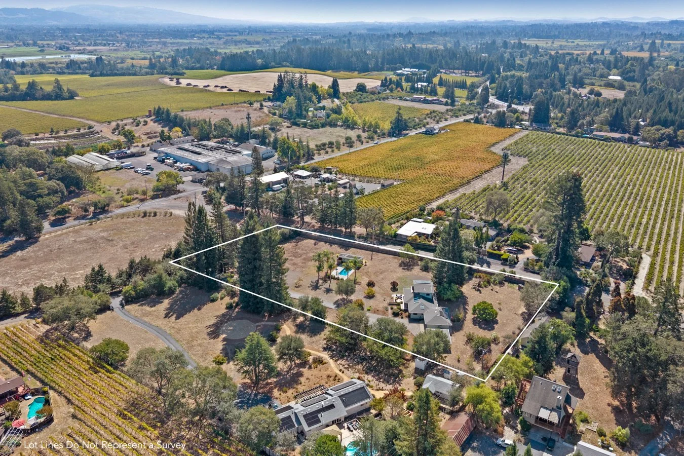 Aerial view of a residential property with a outlined lot, trees, a house with a swimming pool, and neighboring farms and fields.