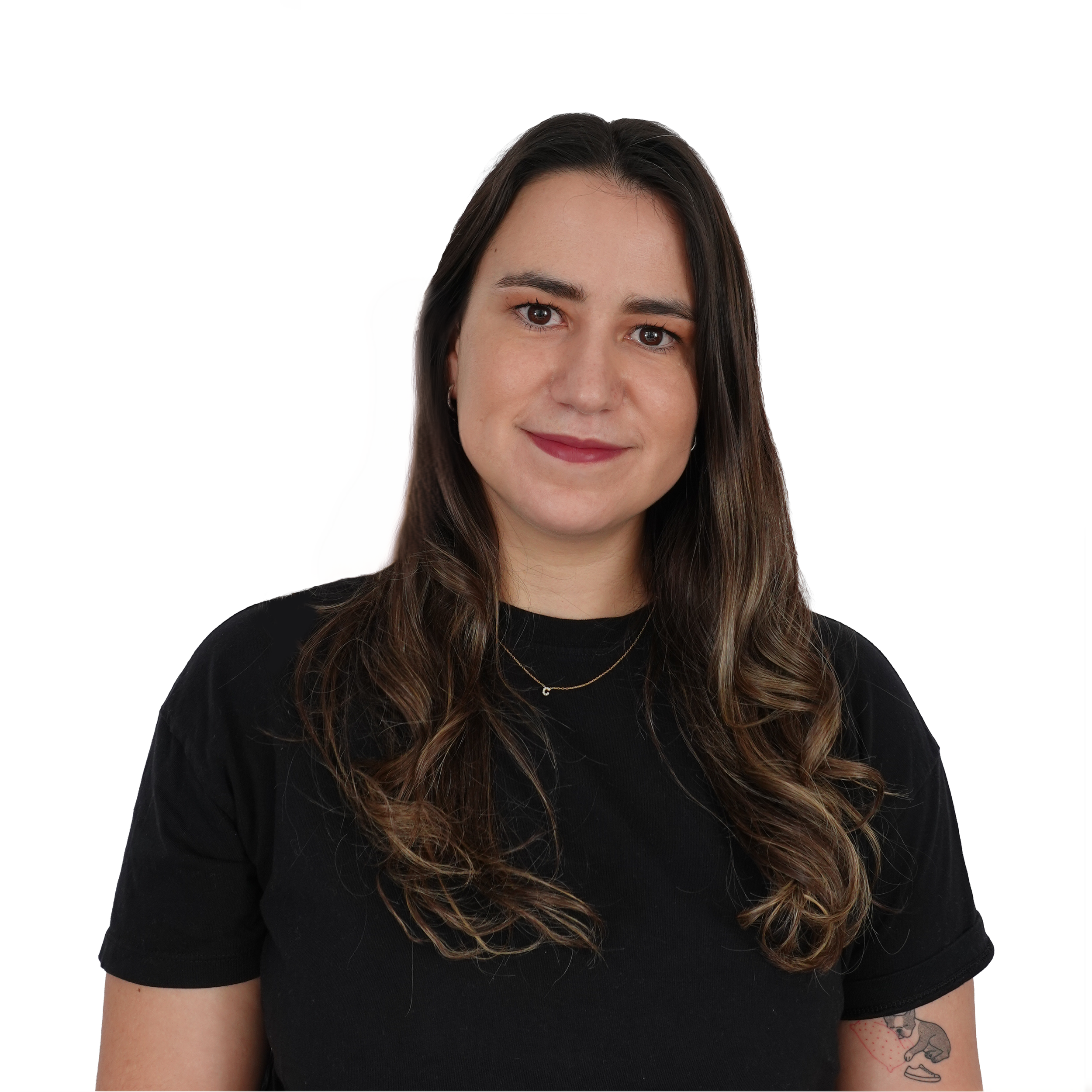 Close-up of a woman with dark brown hair and a tattoo on her arm, wearing a black shirt and a delicate necklace, against a white background.