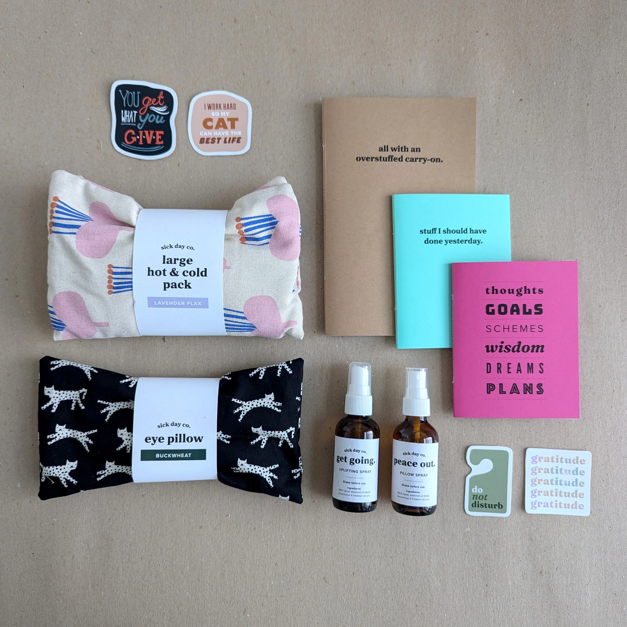 A beige background with various items attached, including motivational stickers, a fabric pouch with a floral design labeled 'large hot & cold pack,' two small spray bottles, and various colored sticky notes with quotes on them.
