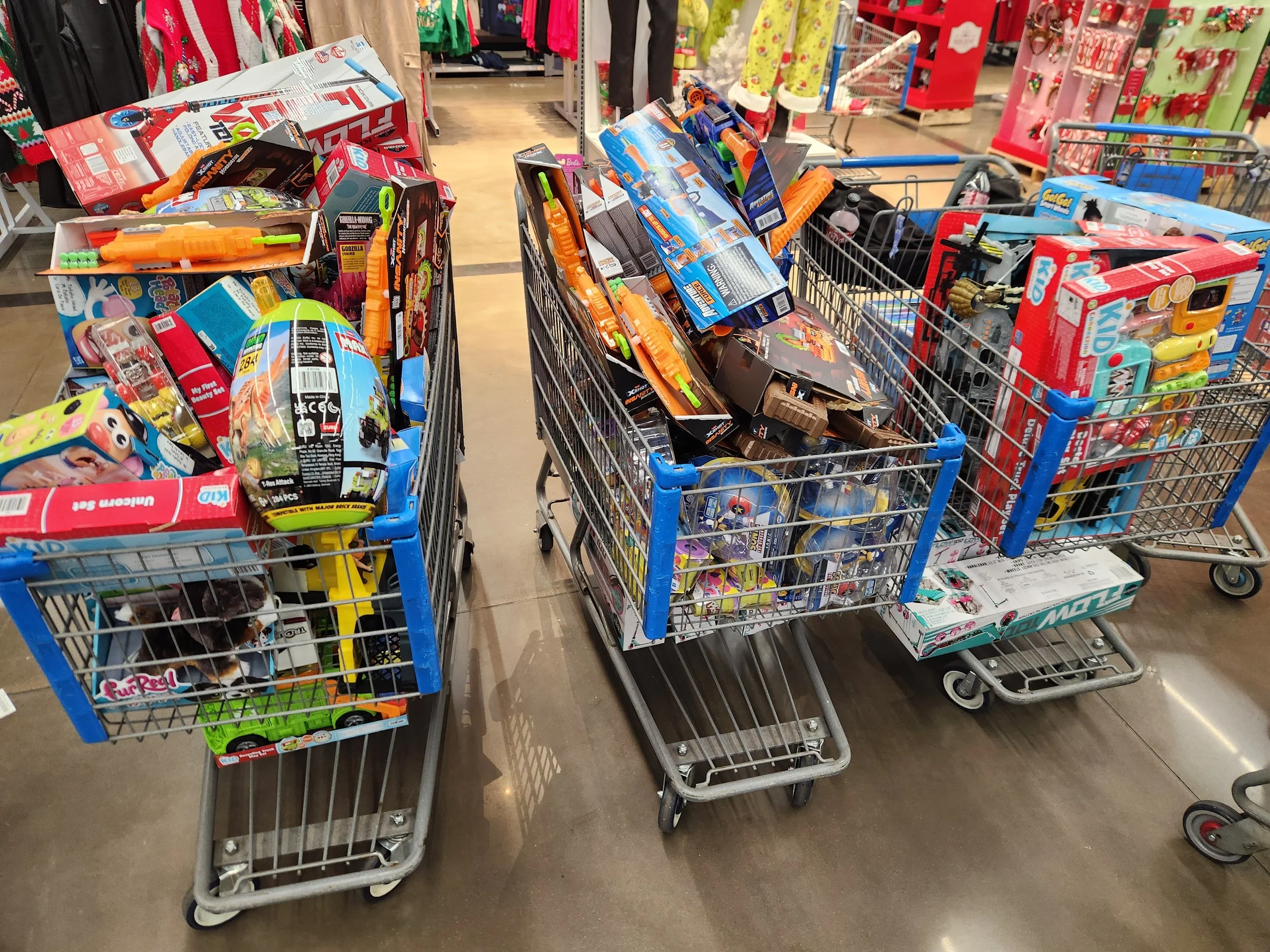Shopping carts filled with toys and merchandise inside a retail store. Shelves and clothing in the background.