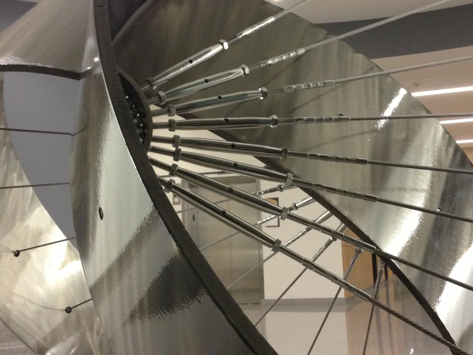 Close-up of a large metallic sculpture with multiple long, thin rods arranged in a circular pattern, attached to large metal rings.