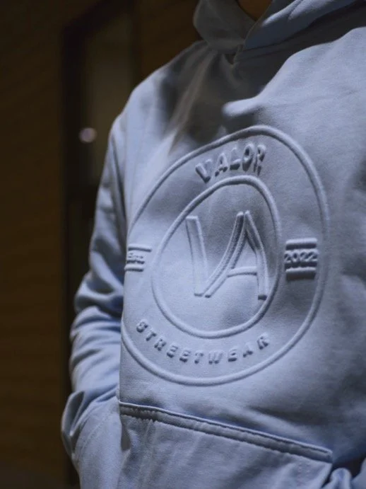 Close-up of a light gray hoodie with an embossed logo and text reading "Vapor" and "1992."