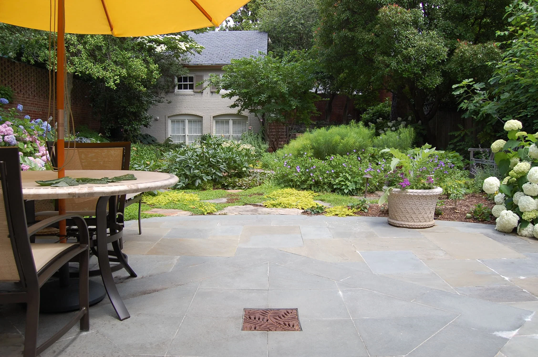 Colorful plantings and a natural stone patio in a very private back yard garden design in Georgetown, DC. Beautiful outdoor furniture for al fresco dining.