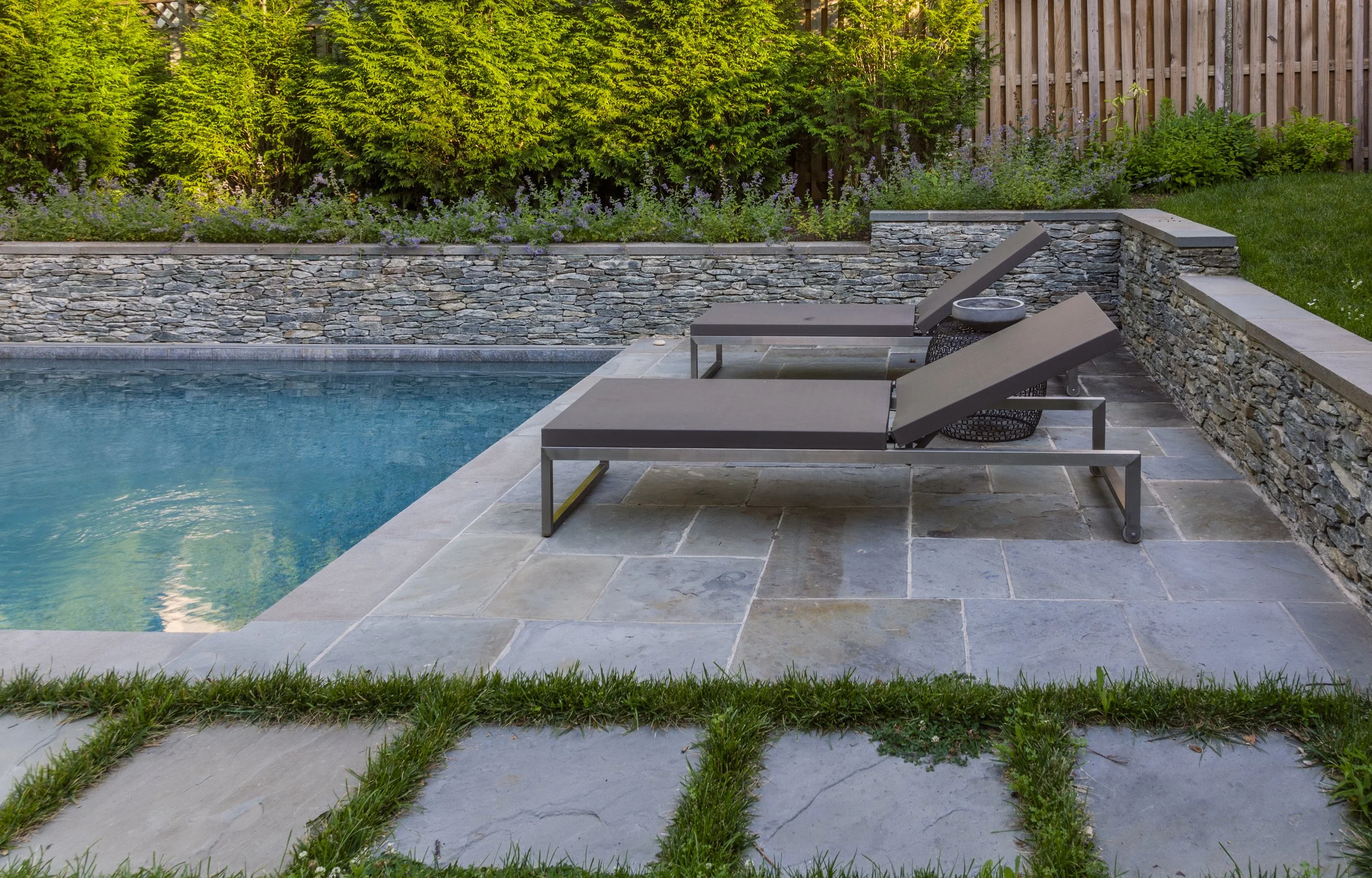 Clean lines, precise hardscape, retaining wall, natural stone, swimming pool, screening plantings in Northern Virginia