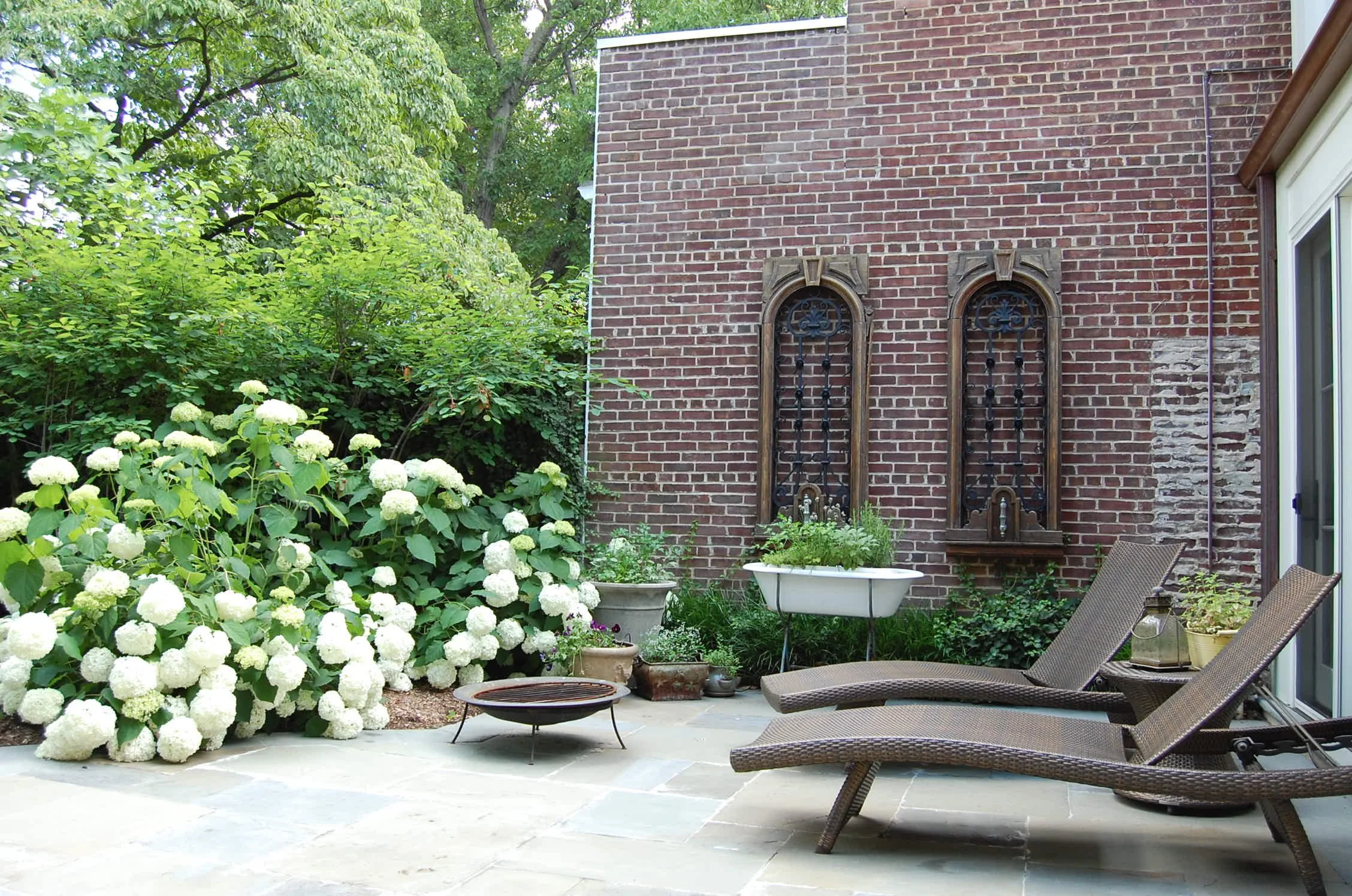 Bold, colorful plantings contrast with old brick walls, smooth new natural stone patio. Lounge in the sun in a private back yard in Georgetown, DC