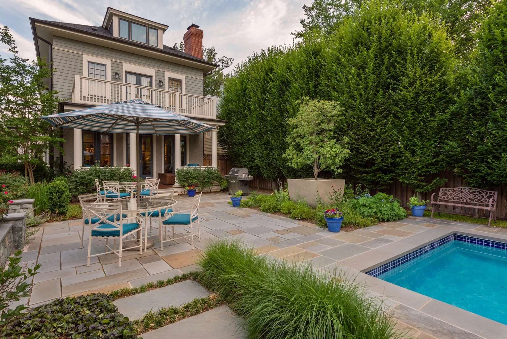 Traditional NW DC foursquare garden design w/ expansive back porch. Entertaining spaces in natural Bluestone + an inviting in ground swimming pool. Lush, dense plantings create a privacy screen + the large scale concrete planter becomes a focal point
