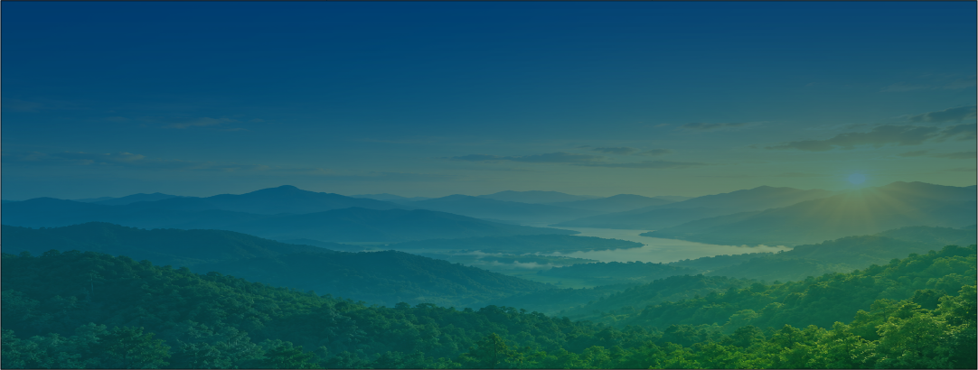Sunrise over green mountain range with misty valley below.