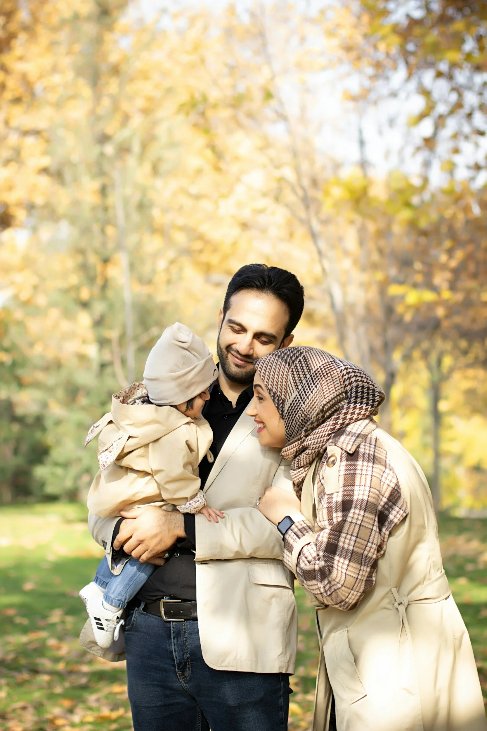A family enjoying a fall day in a park with colorful autumn leaves.