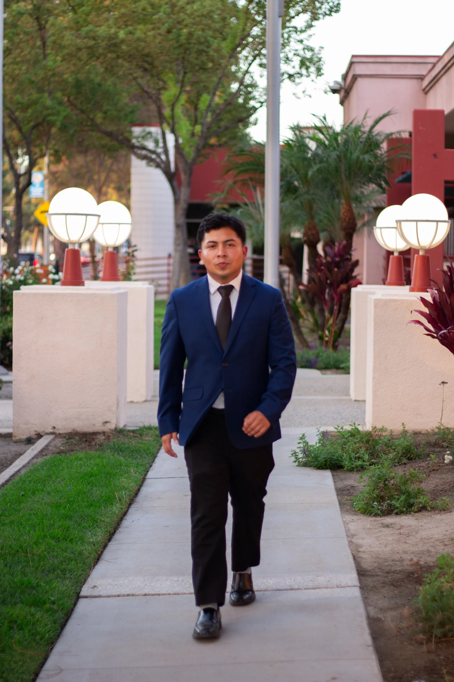 Samuel Perez walking along a landscaped outdoor pathway.