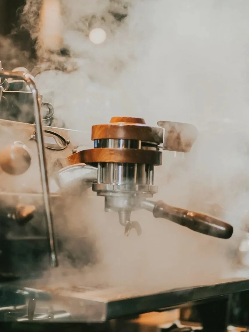 Steam rising from the wand of a café espresso machine