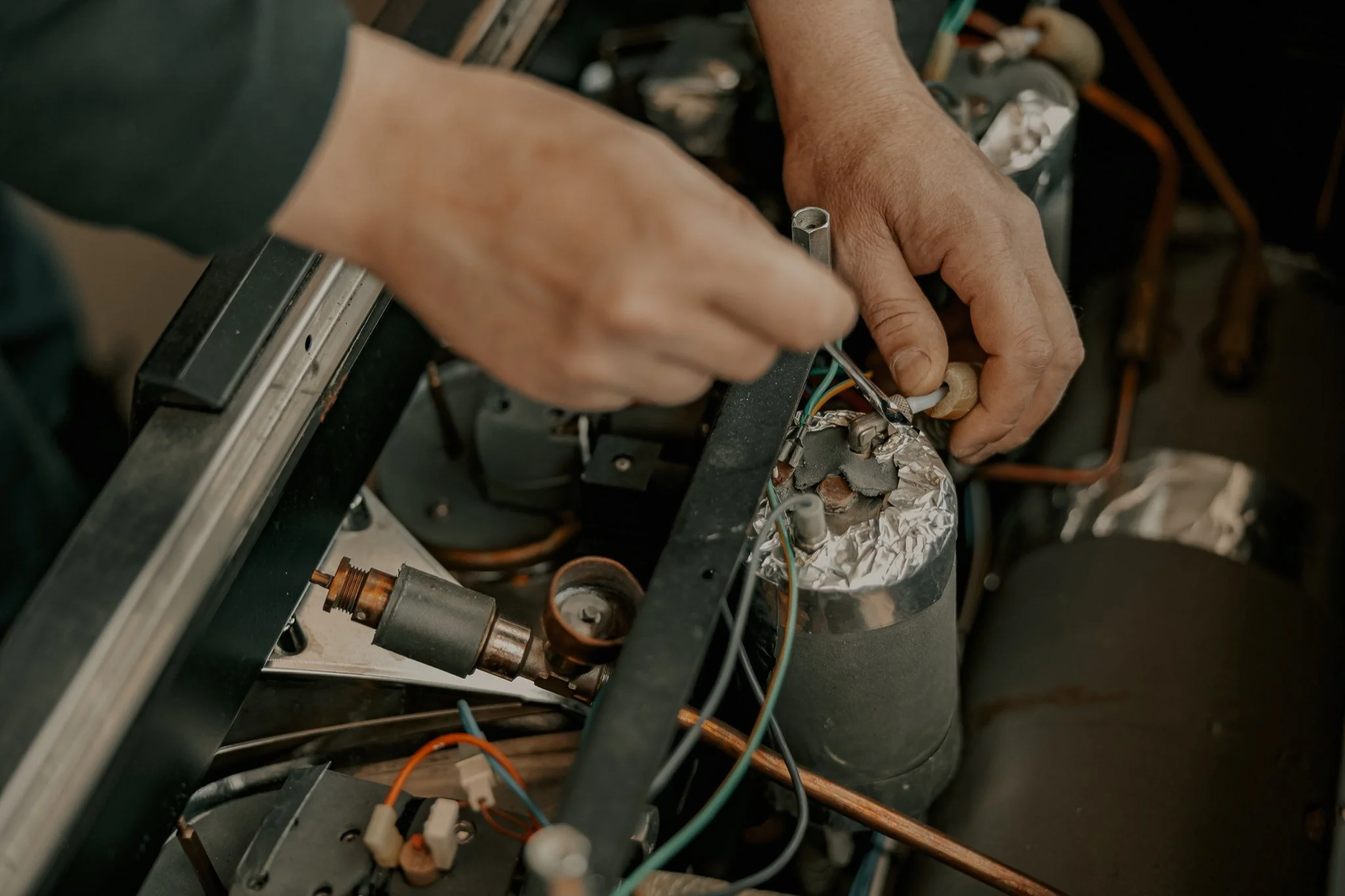 Hands repairing the internals of a commercial espresso machine
