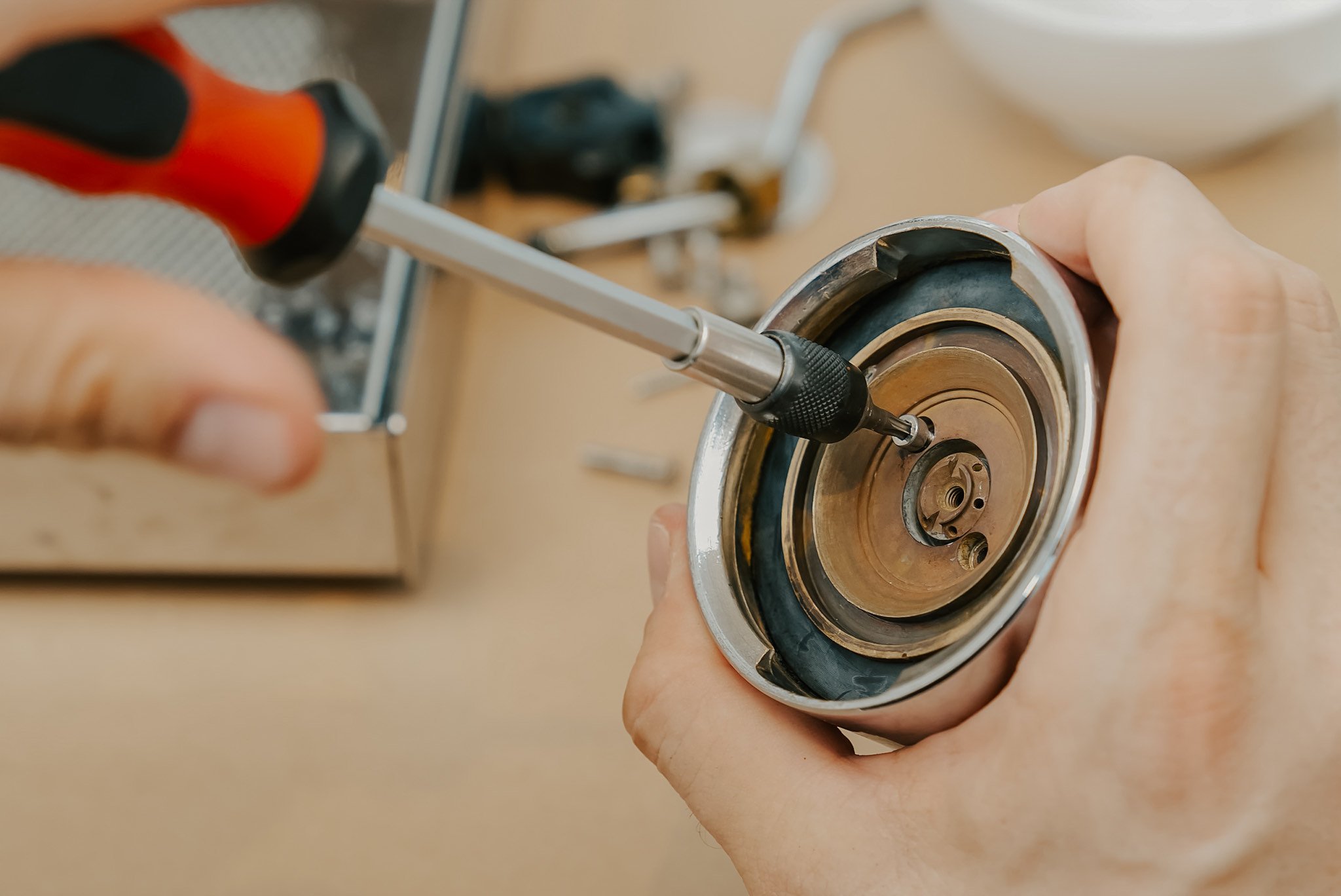 A screwdriver working on an espresso machine shower screen