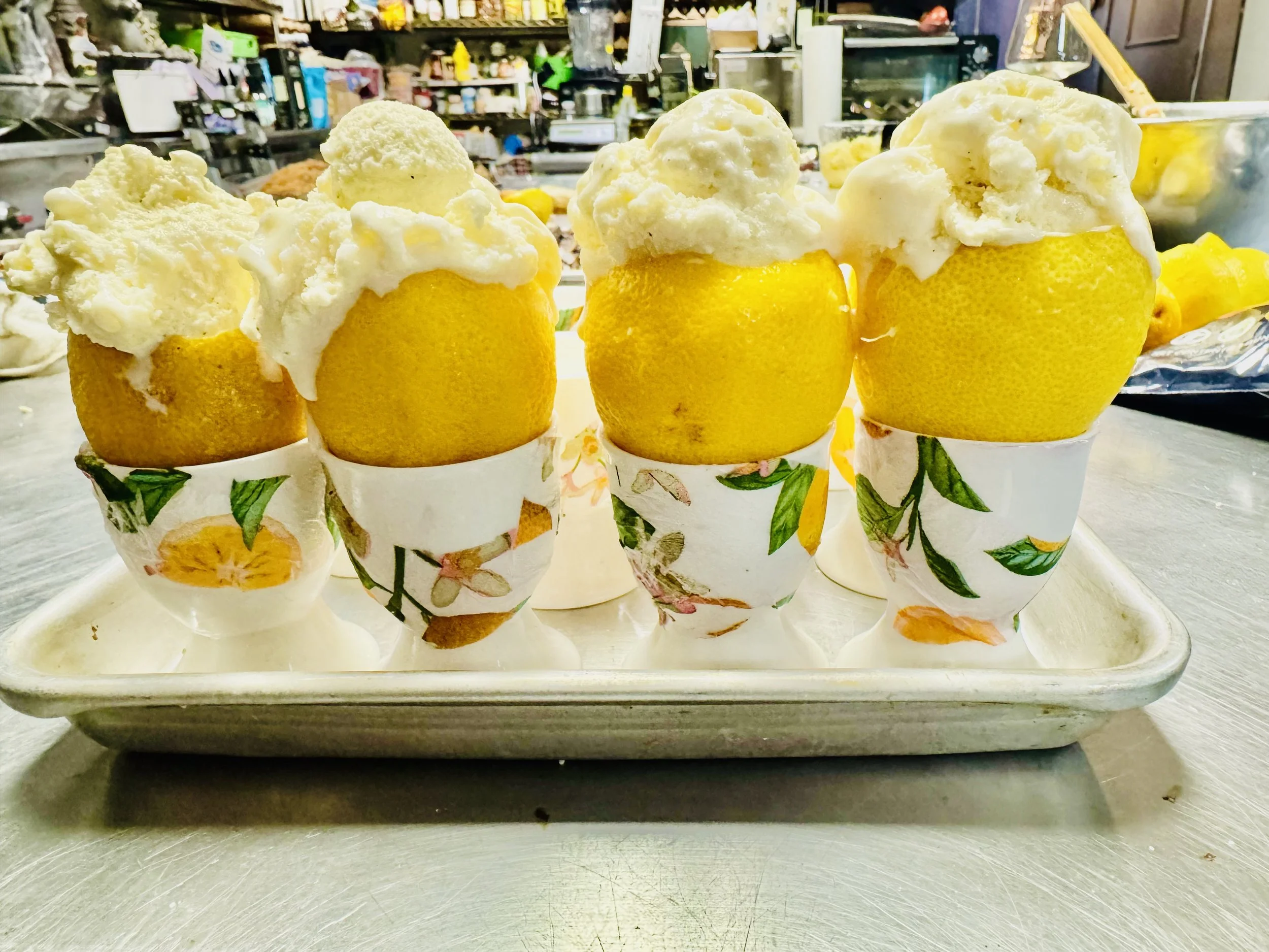 Lemon cups filled with lemon-flavored ice cream or sorbet, placed on a tray with a floral design.