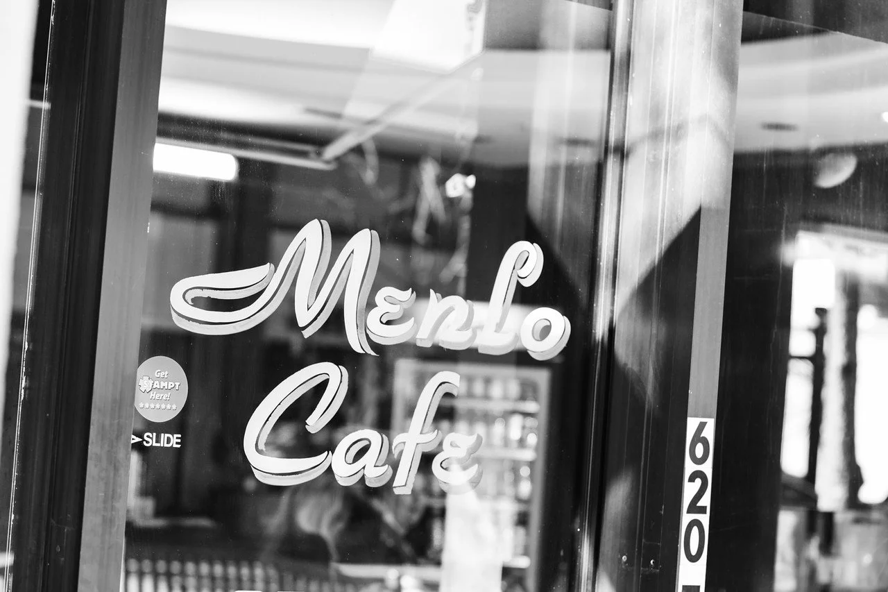 Sign on a glass door reading 'Menlo Cafe' in cursive font, with the street number 620 next to it.