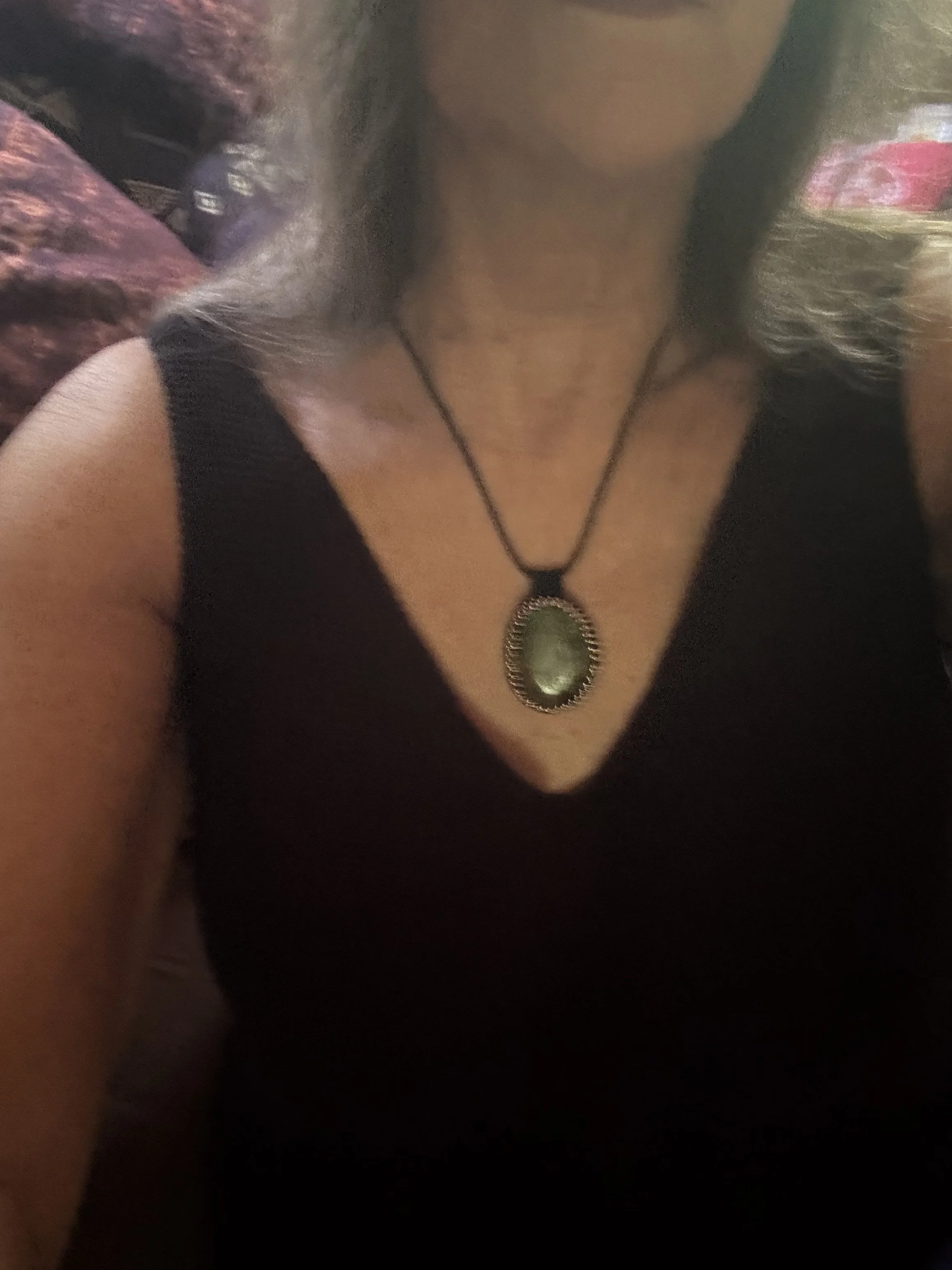 Close-up photo of a woman wearing a black top with a turquoise pendant necklace with beaded bezel.