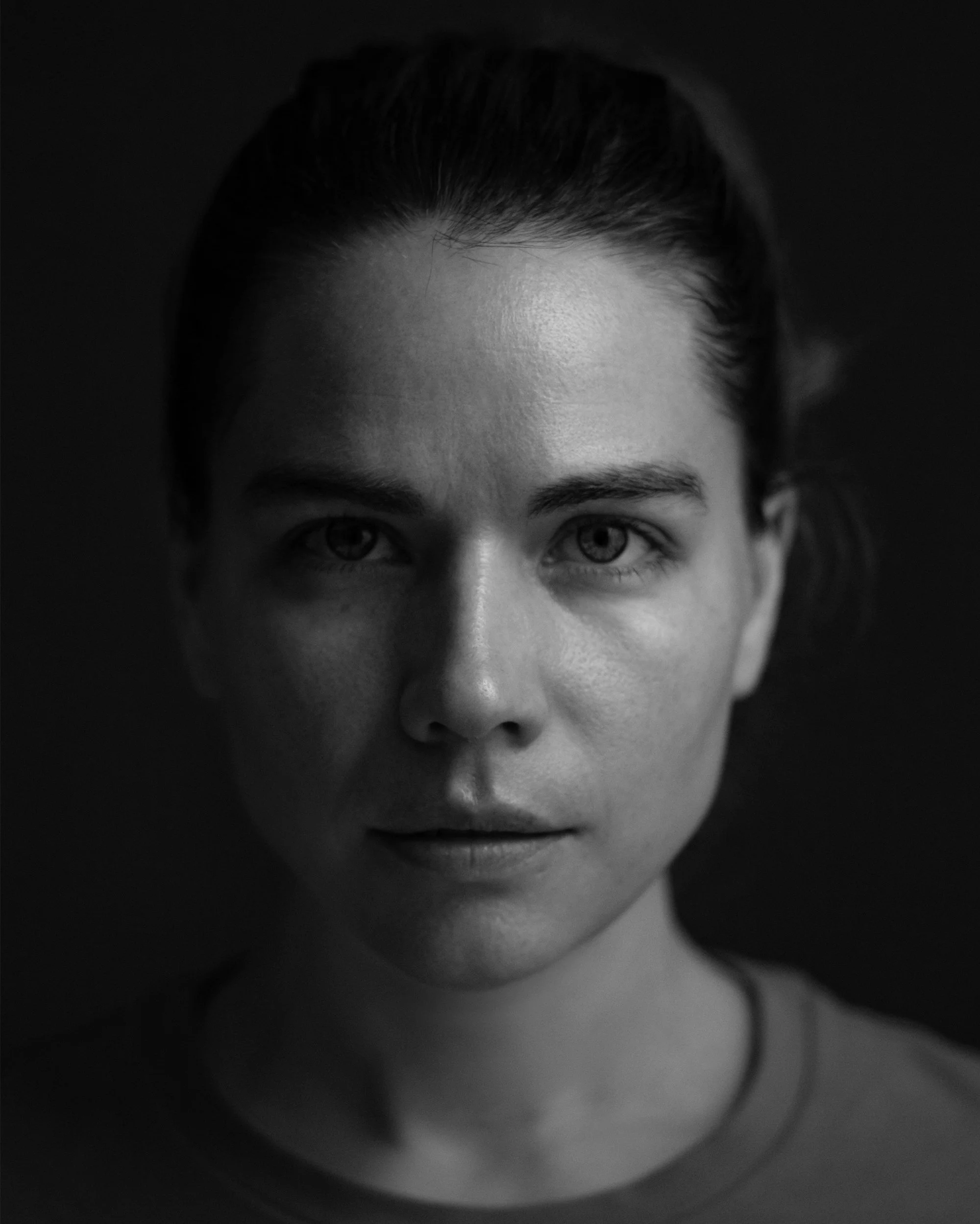 Jennifer Mcd. Writer & Producer. Close-up black-and-white photo of a woman's face, focusing on eyes, forehead, and nose, with dark hair pulled back.