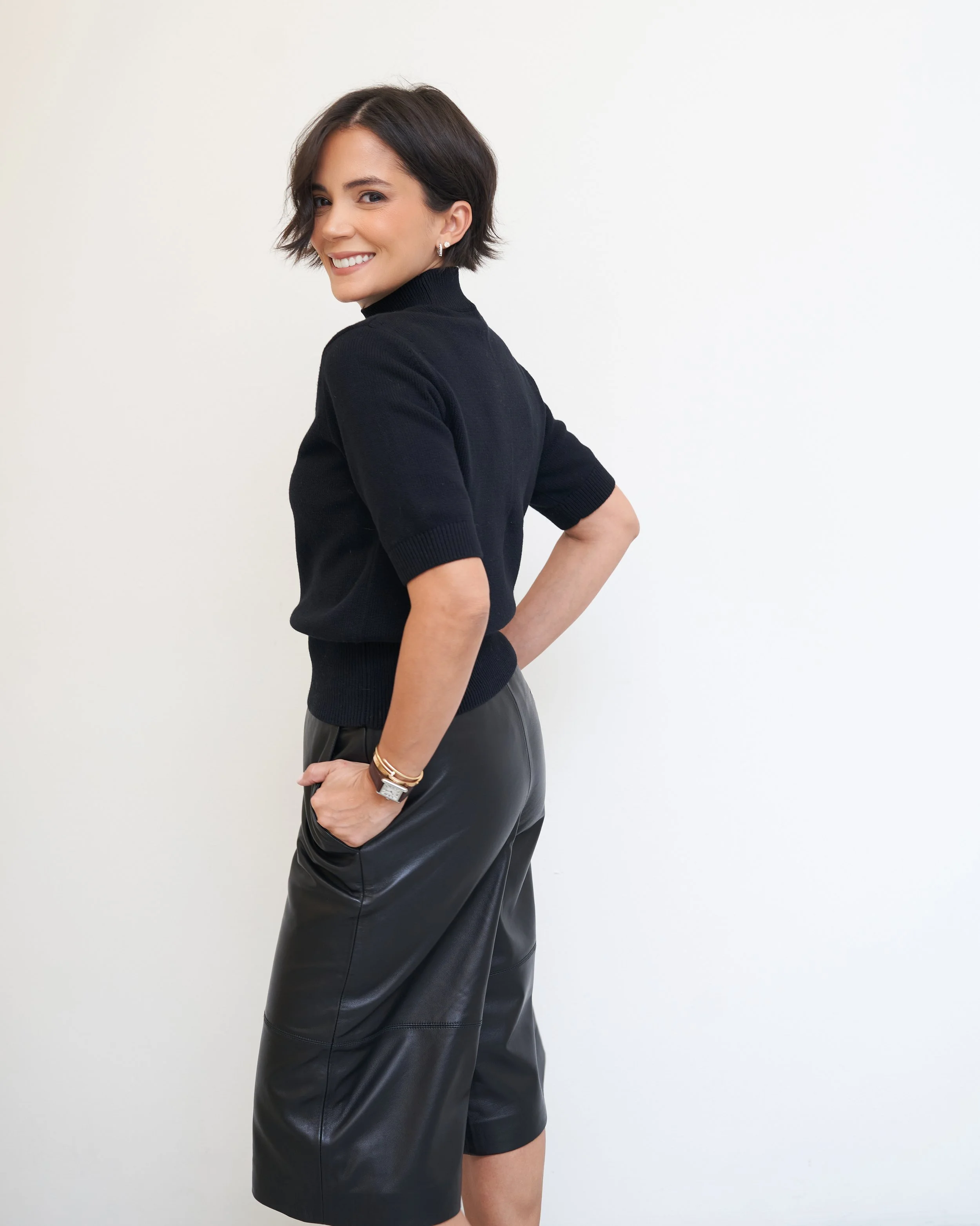 Black short-sleeve turtleneck with a black leather skirt and gold accessories