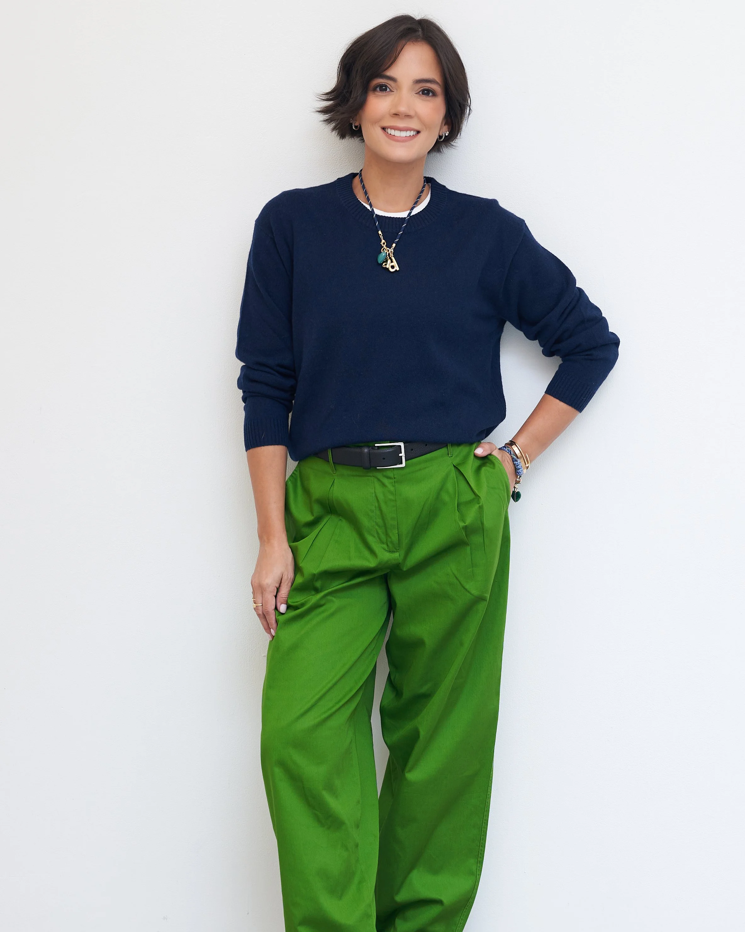 Navy sweater with green pleated trousers, a black belt and gold jewelry