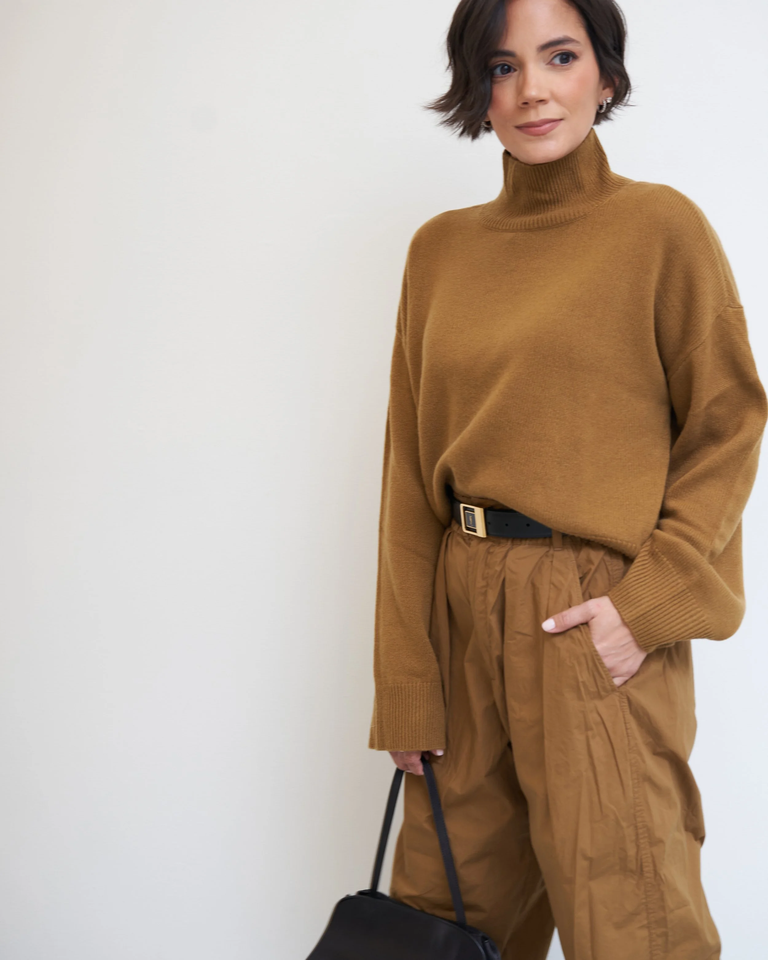 Camel turtleneck sweater with belted camel trousers and a black handbag