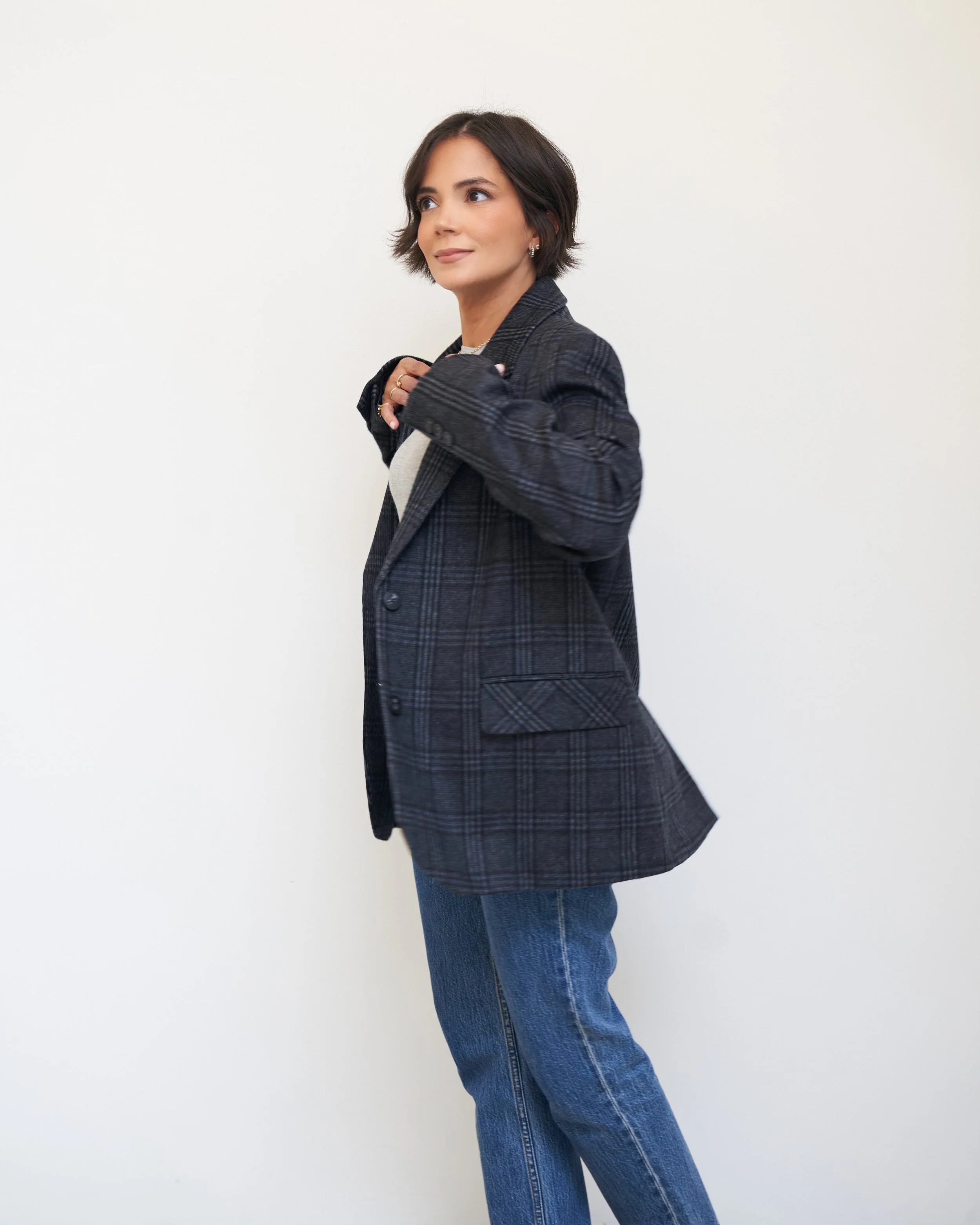 Navy plaid blazer worn over a dark top with straight-leg blue jeans