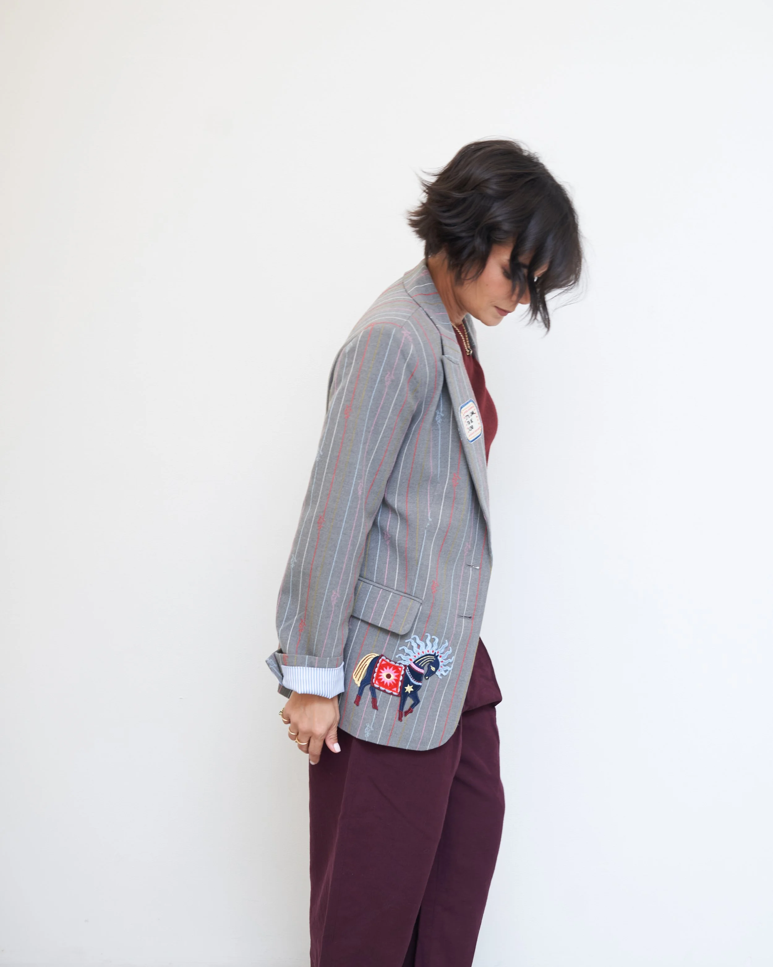 Grey check blazer with burgundy trousers and a playful embroidered patch