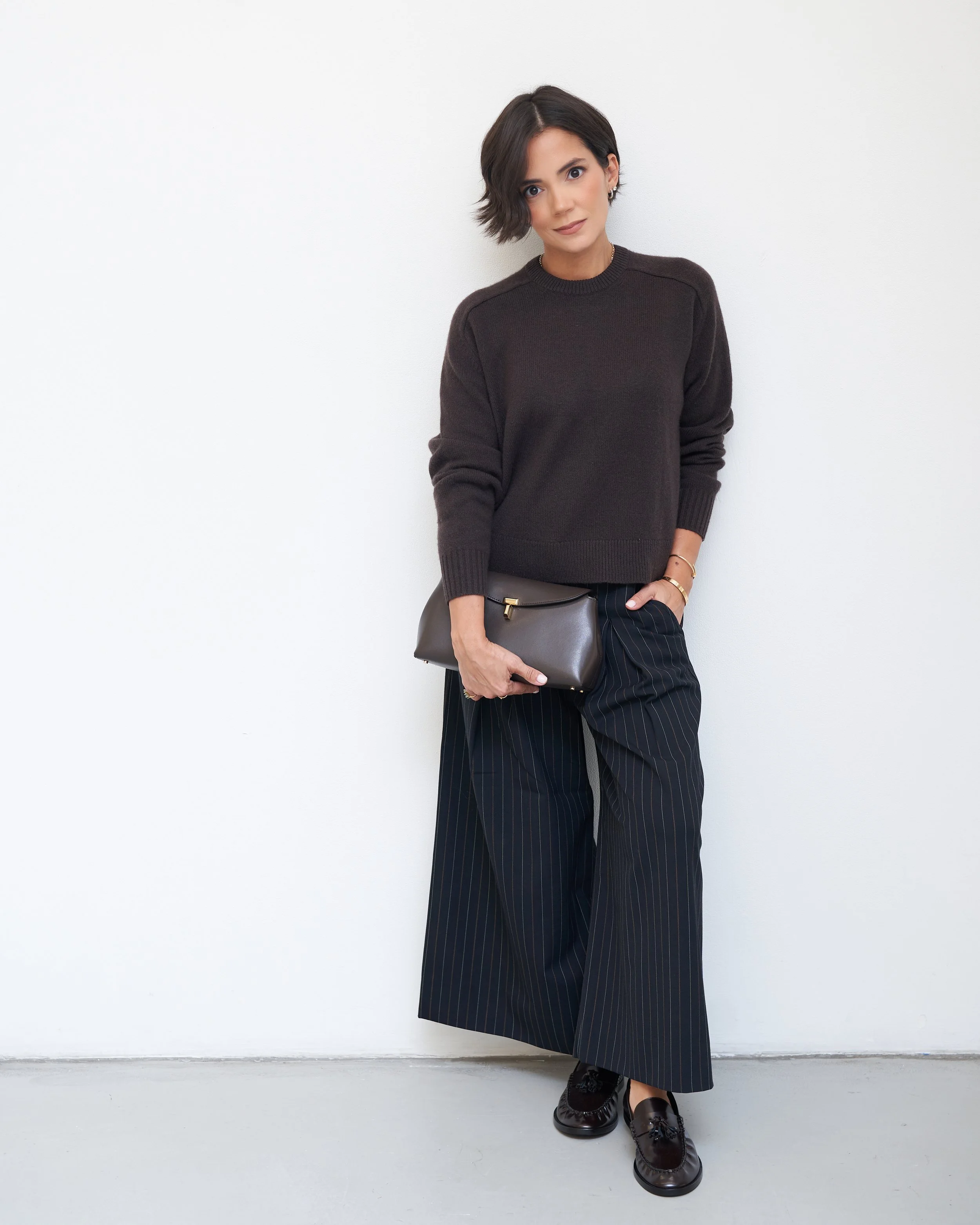 Brown crewneck sweater with black pinstripe wide-leg trousers, loafers and a structured bag