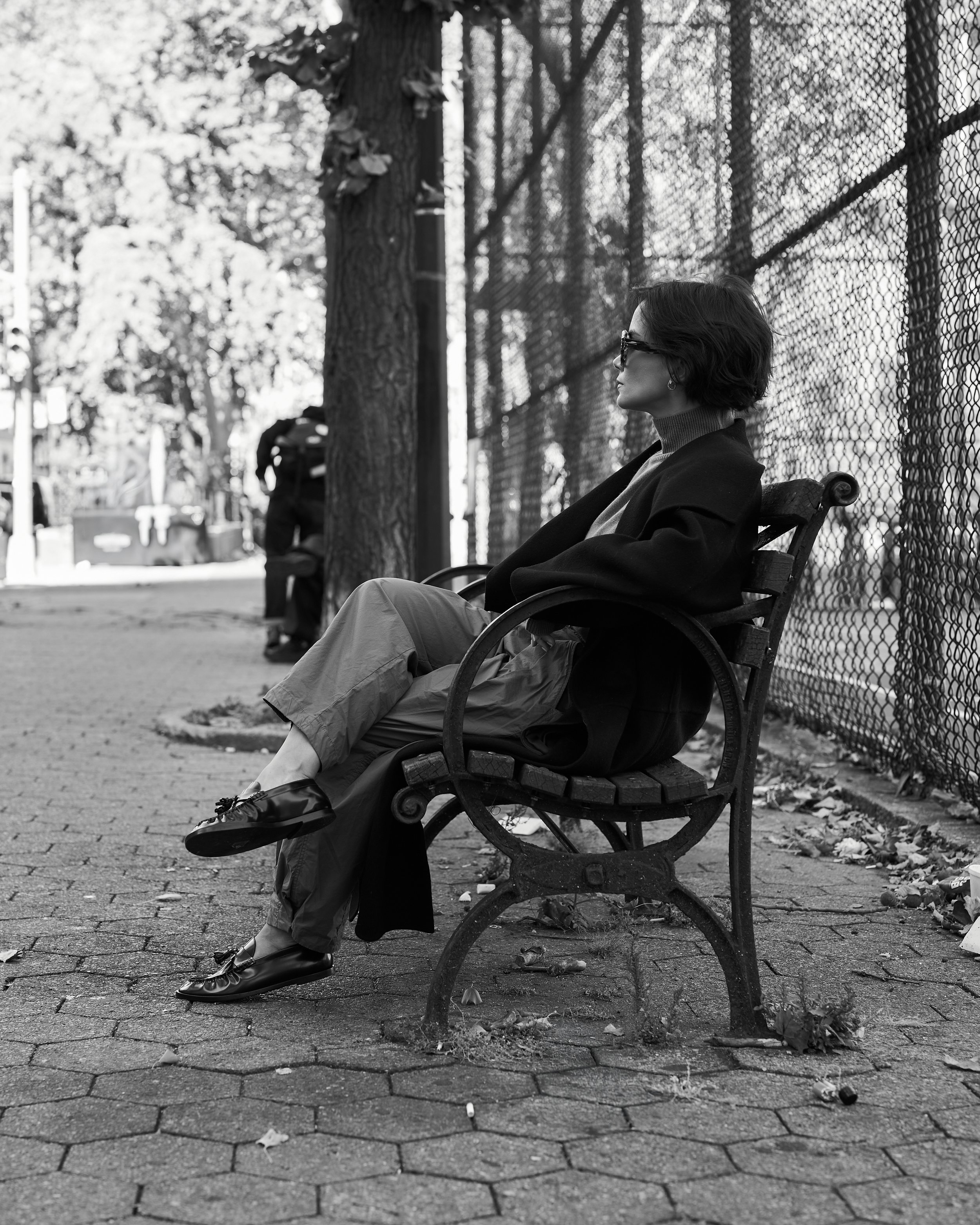 Black and white photo of a relaxed layered look on a park bench in the city