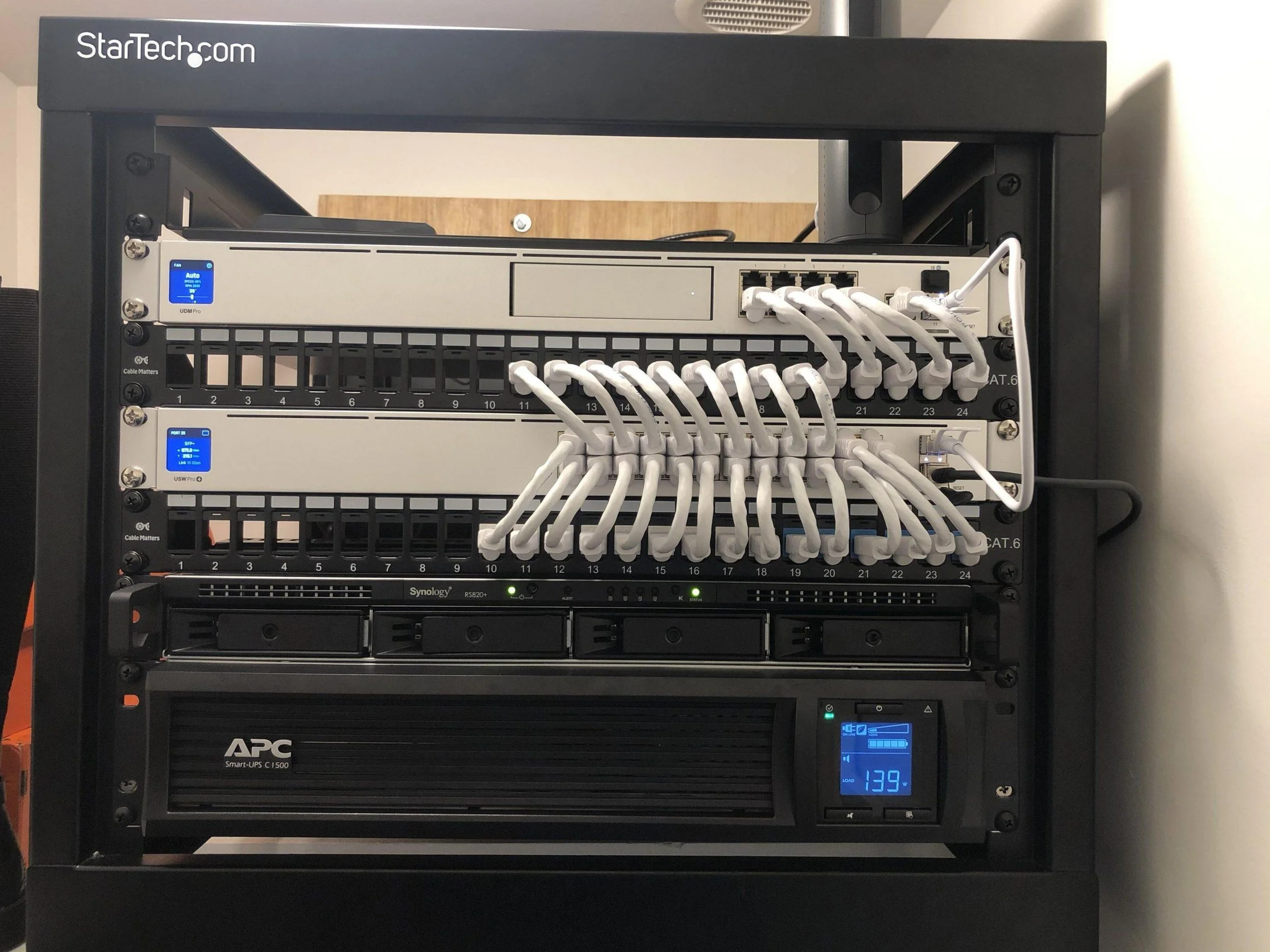 Professional network rack with patch panels, Ethernet cabling, network equipment and rack-mounted UPS.