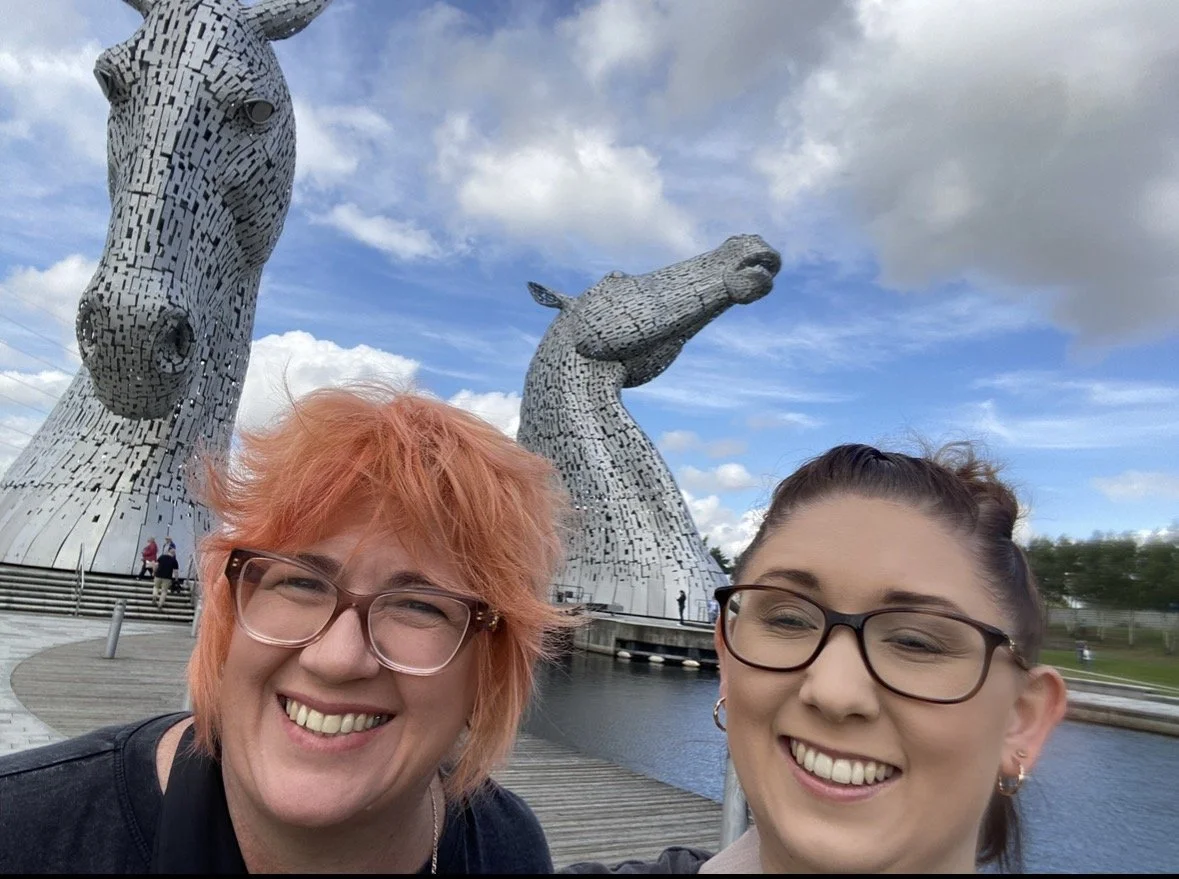 Two women take a selfie beside The Kelpies horse-head sculptures in Falkirk, Scotland.