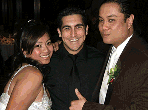 Three people posing together, smiling, dressed in formal attire at a social event.
