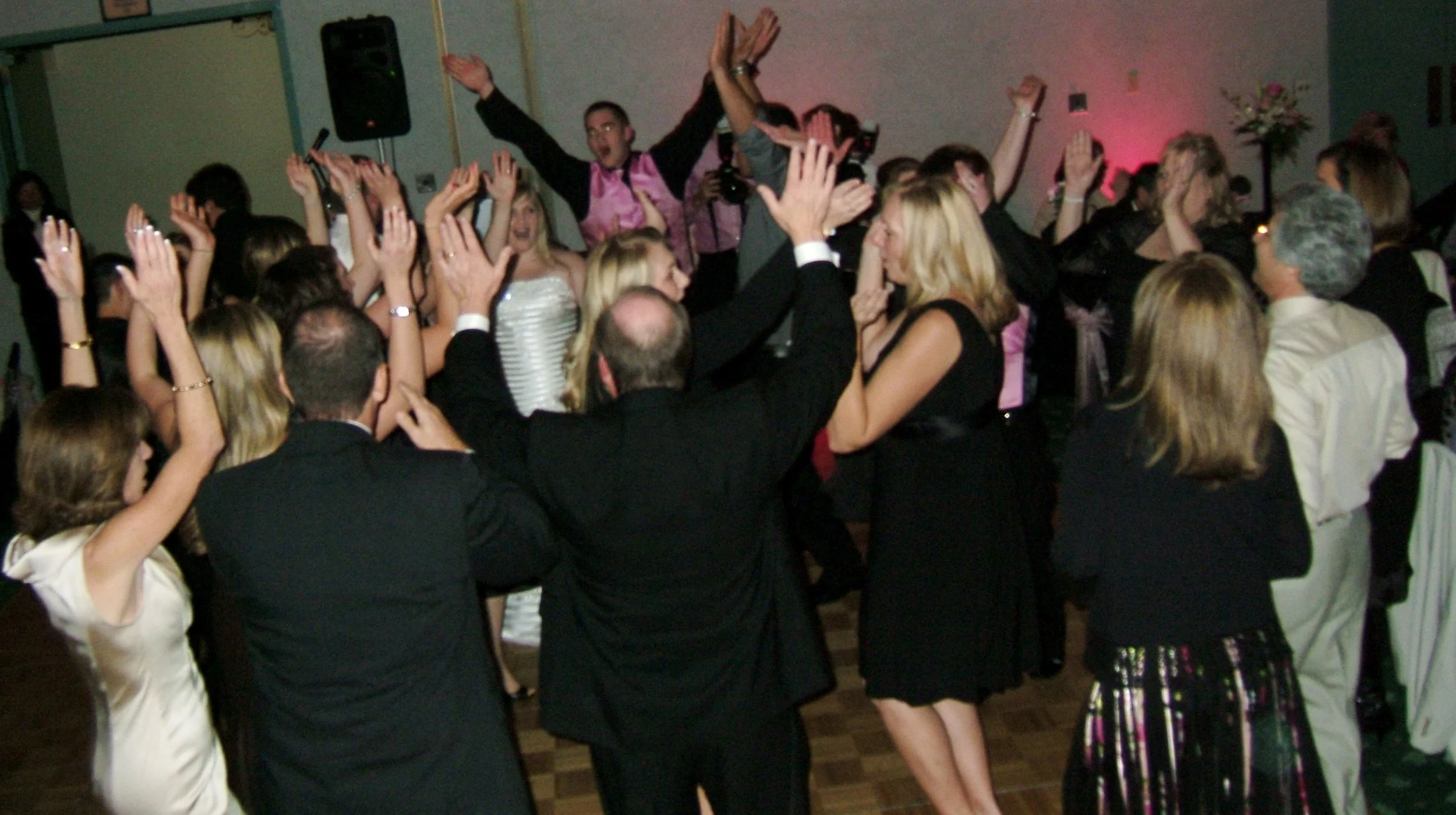 Group of people dancing and celebrating at a party with raised hands and a lively atmosphere.