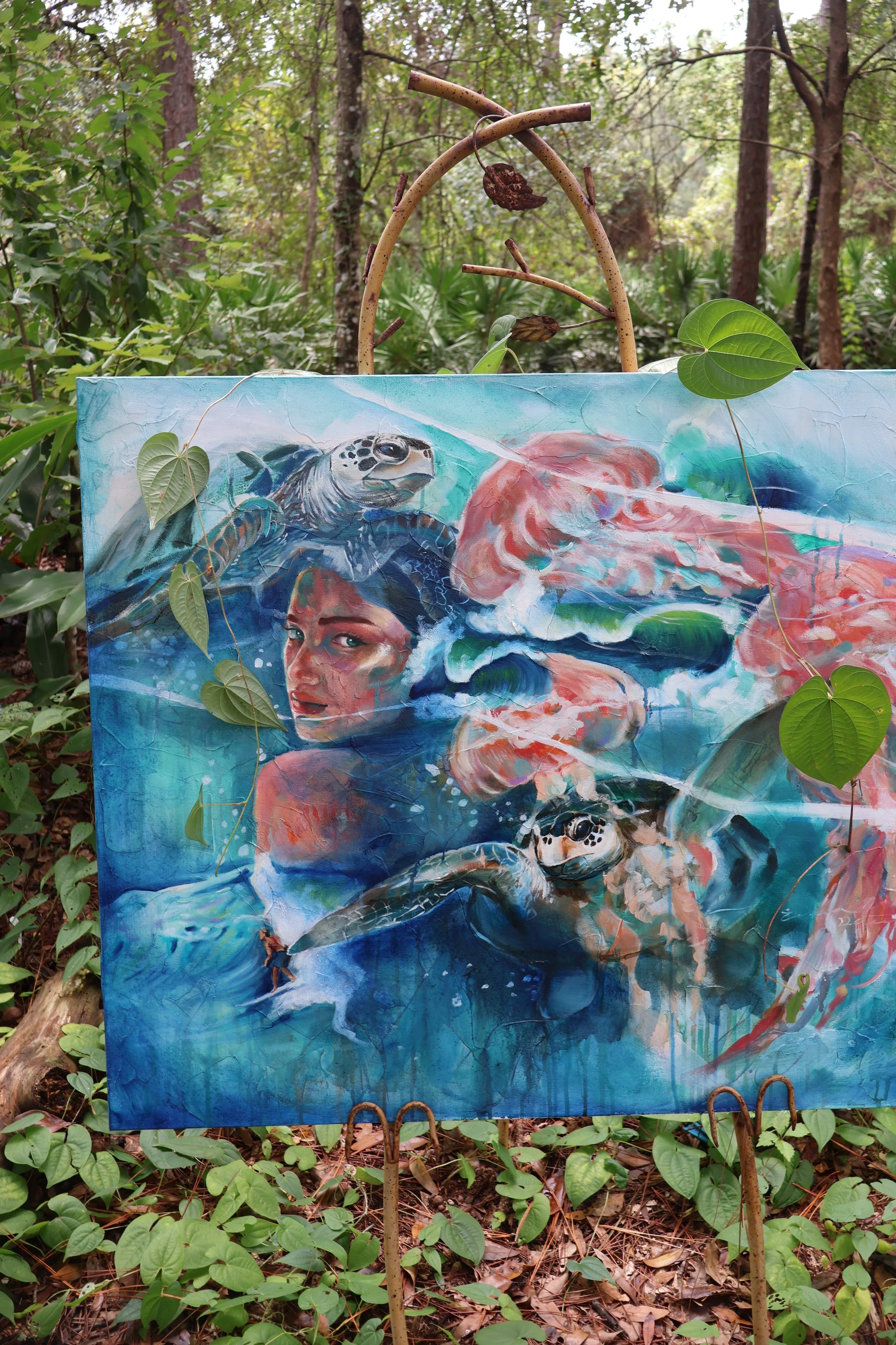 Colorful painting of sea turtles and abstract figures displayed in a wooded forest clearing