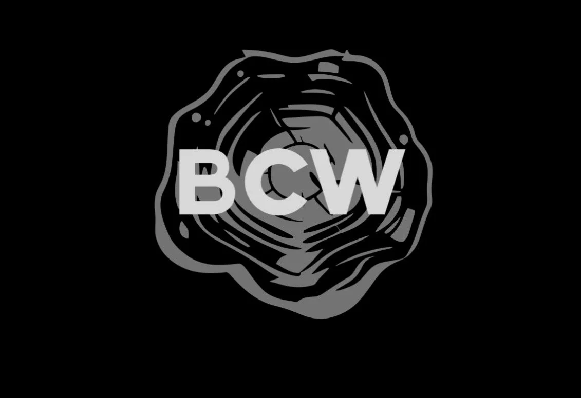 Silhouette of a tree cross-section with the letters BCW over it, all in gray on a black background.