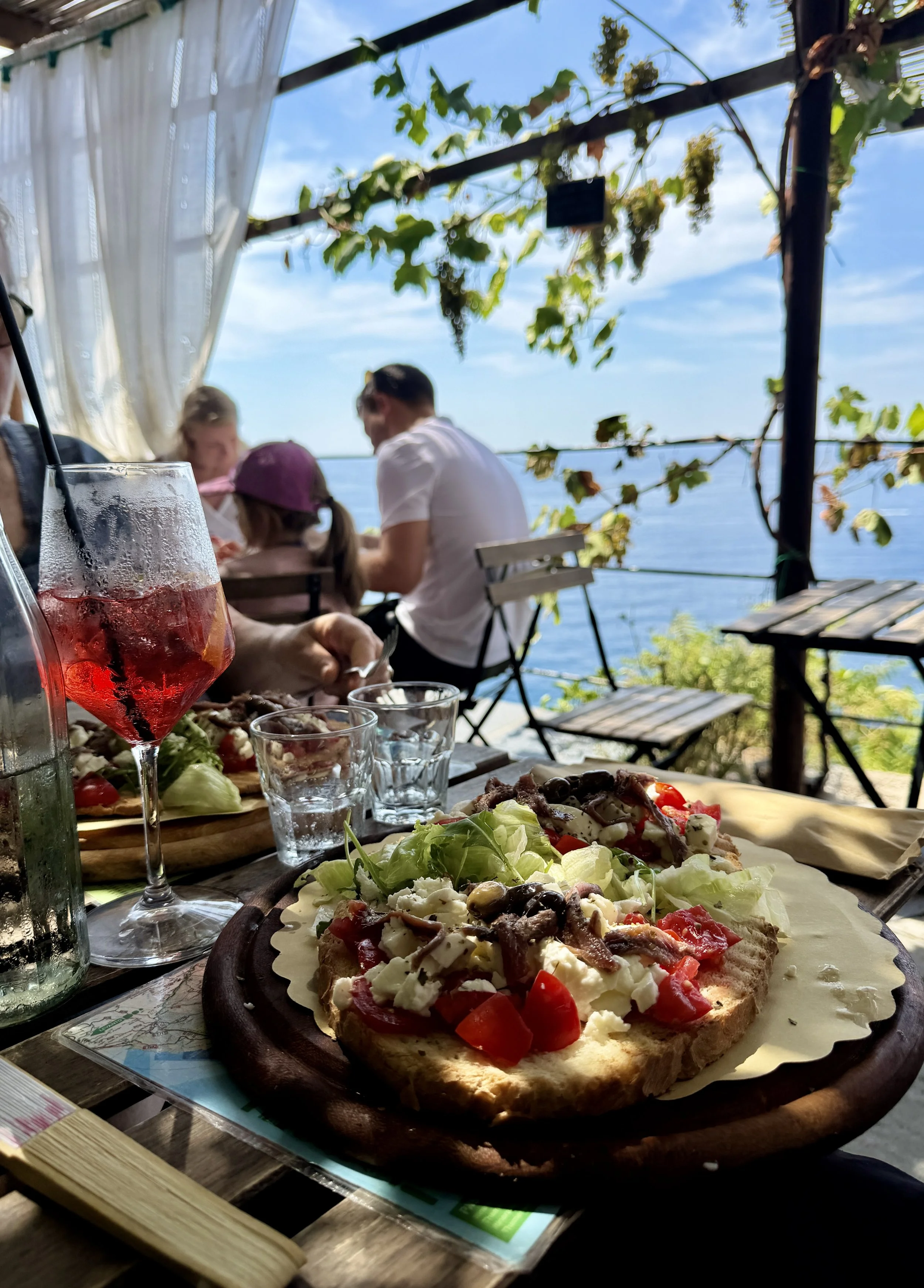 Taste the Ligurian focaccia with tomatoes, cheese, and local olives.
