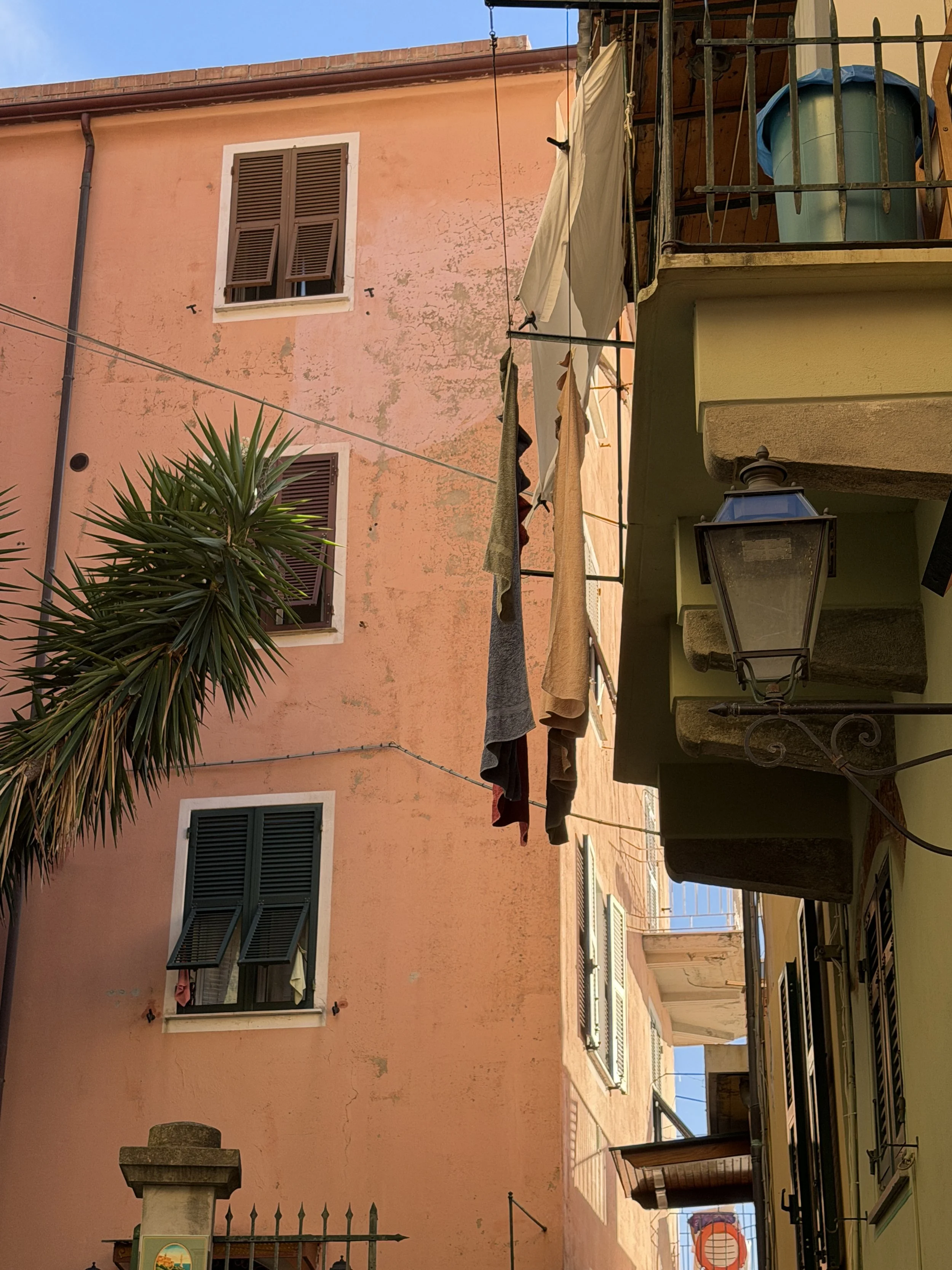 View of Santa Margherita Ligure with pastel-colored buildings, laundry hanging outside, and outdoor furniture on a terrace.