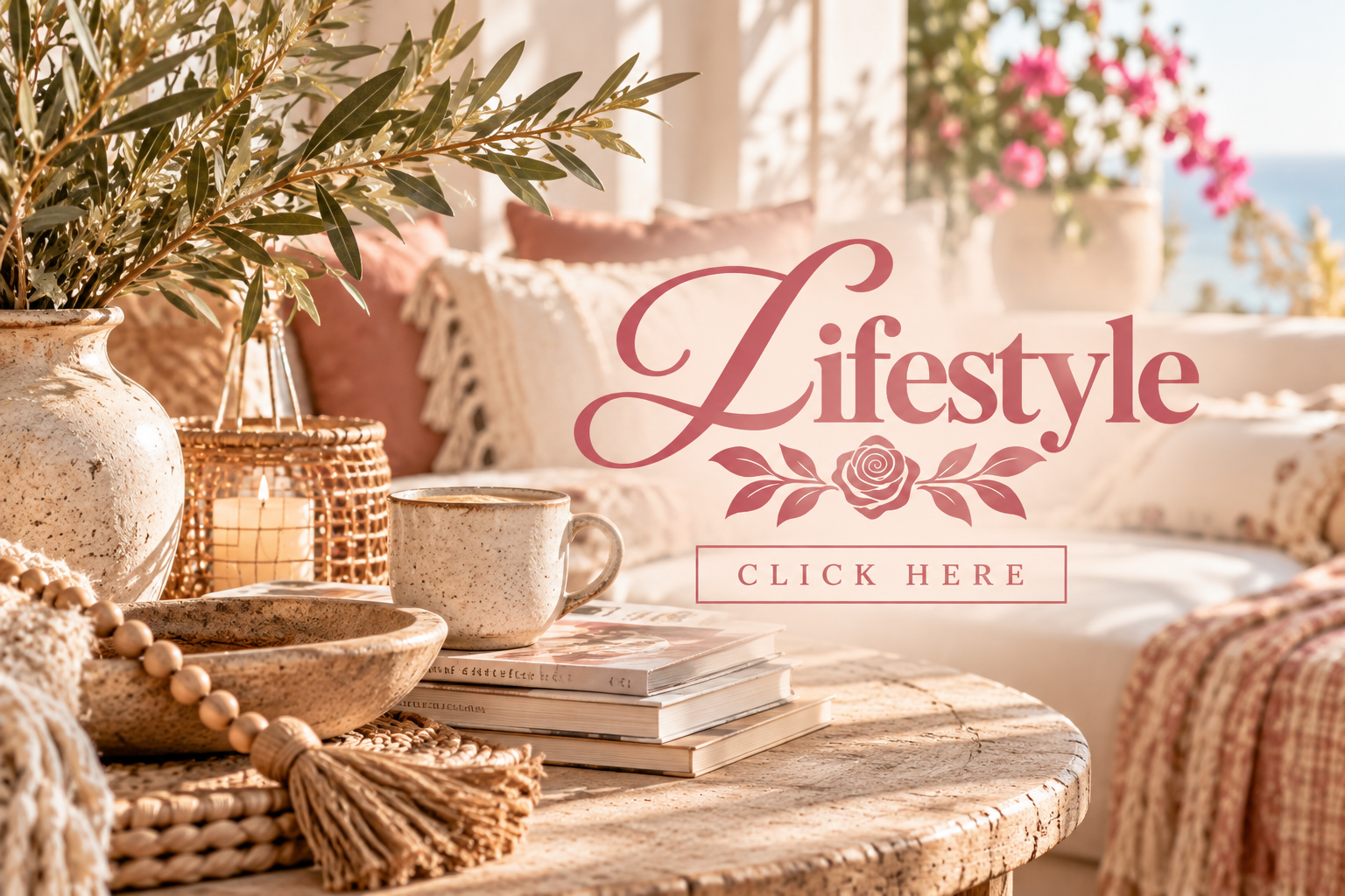 Decorative living room with a rustic round table holding a ceramic lamp, a beige striped cup, and a stack of magazines. In the background, there are floral cushions, a large white vase with greenery, pink flowers, and a cozy, sunlit atmosphere.